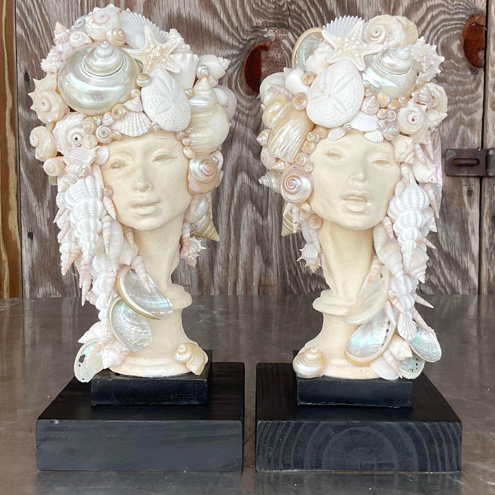 A fabulous pair of vintage Coastal busts. Two chic plaster women in stylish poses. Hand placed shells in a sweeping design. Rest on black wooden plinths.