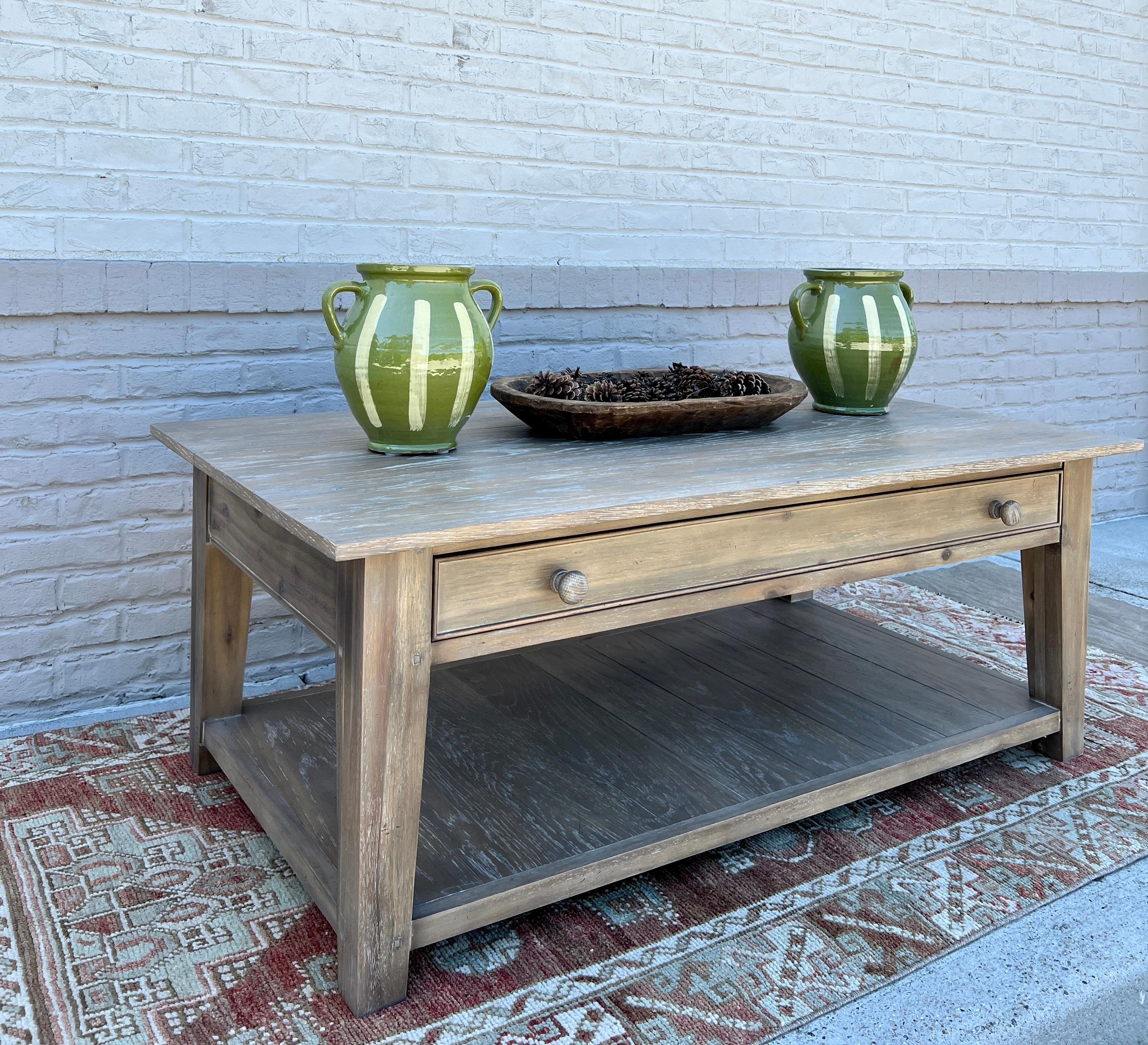 Made in Vietnam, this beautiful coffee table is solid wood with a large dovetailed drawer and lower shelf.

Lightly distressed wood finish.

Discontinued style from Fauld, a superior English furniture company. Excellent condition, used as a showroom