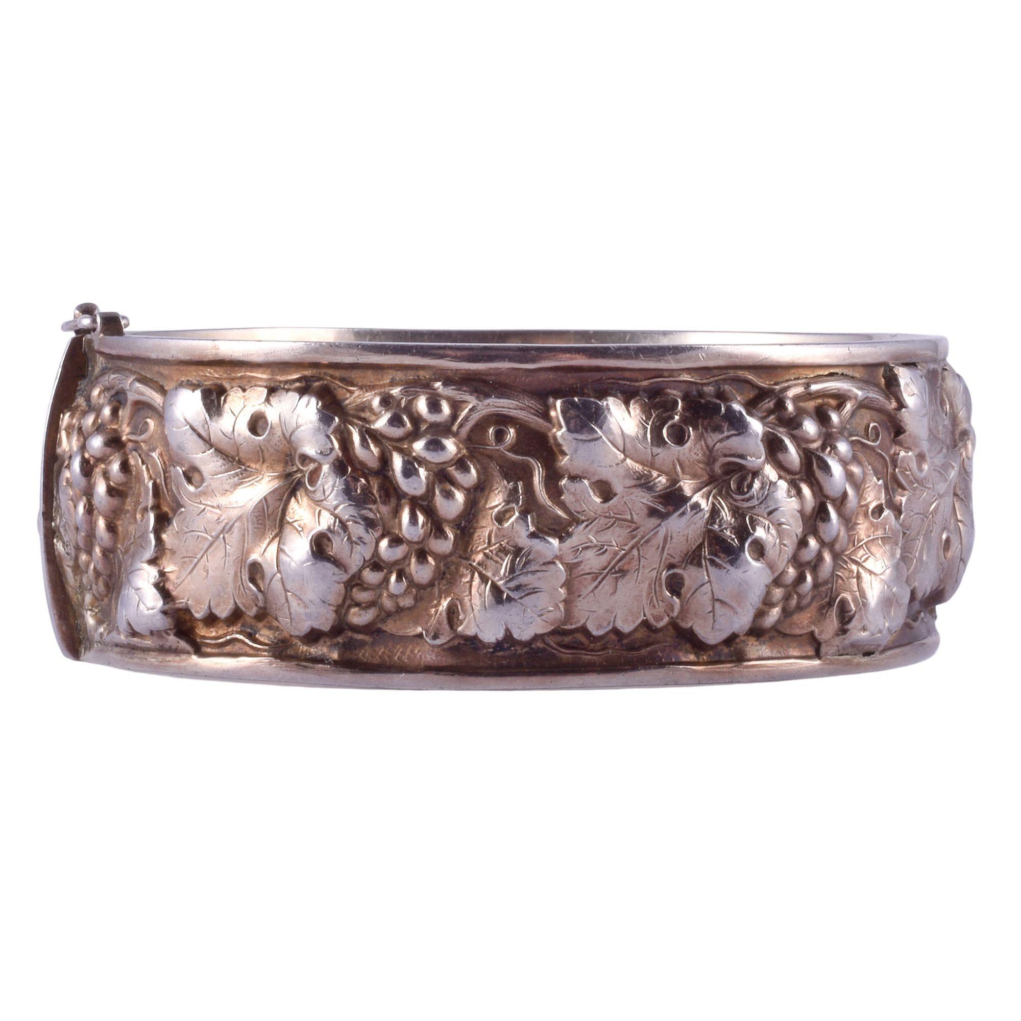 Estate grape vine motif sterling silver hinged bangle bracelet. This bracelet is crafted in sterling silver and marked 925. The high relief grape vine motif continues all the way around this hinged bangle bracelet. This sterling silver bracelet