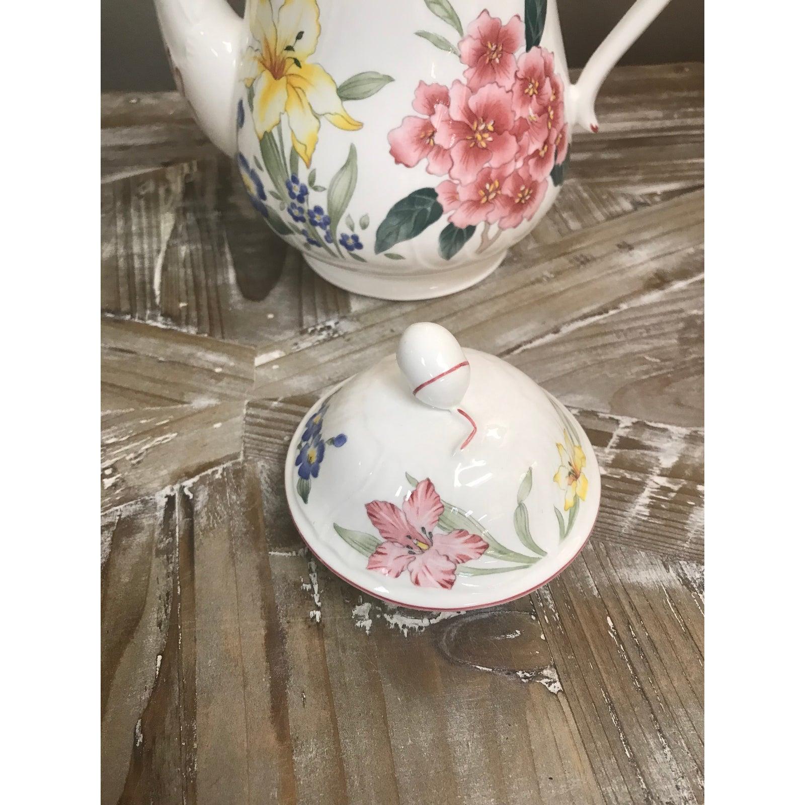 Caffettiera e coperchio Flora Bella di Villeroy & Boch con grandi fiori multicolore su sfondo bianco all'esterno. Il beccuccio, il manico e il bordo del coperchio sono decorati in rosso. Ha una forma a spirale ed è realizzato in porcellana.