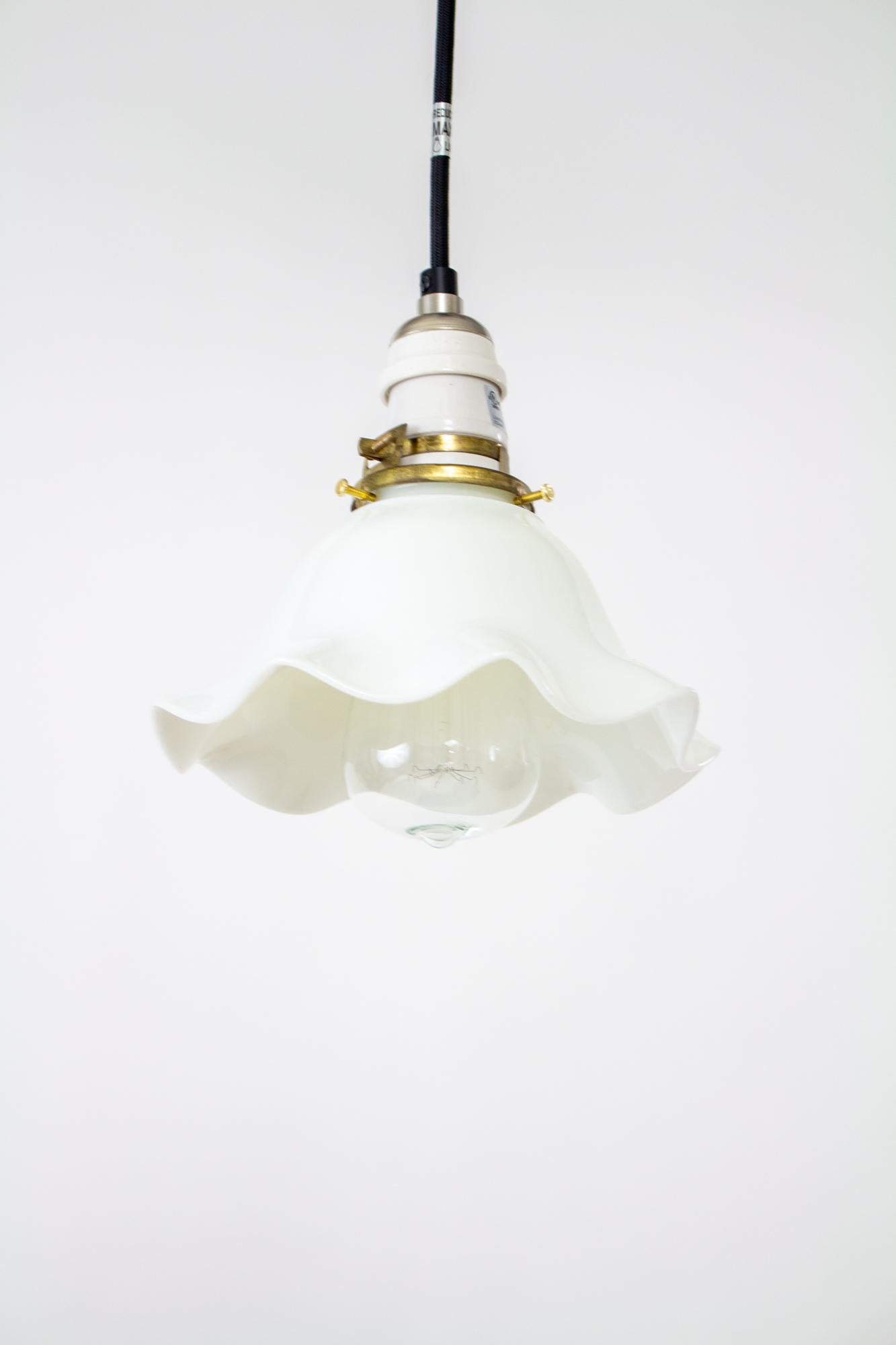 Early 20th century industrial white frilly milk glass pendant. Black cord and canopy, porcelain antique style socket, antique clamp fitter and milk glass disk shade. Shown with Edison style bulb as a style suggestion, bulb is not included. Fixture