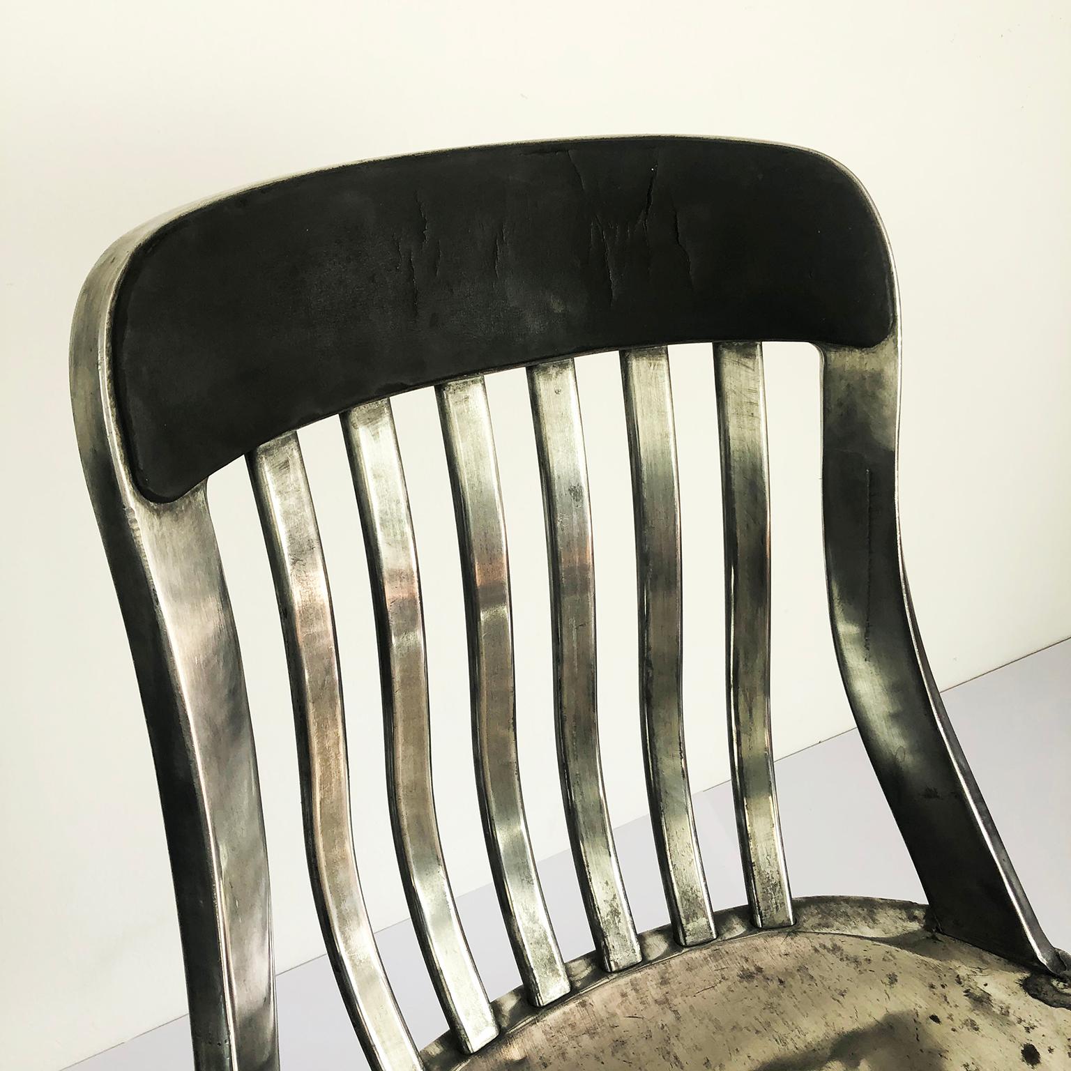 We offer an early original aluminum armchair. Made of cast and formed aluminum with a slatted undulating back and thin leather pad on the top of the backrest with original label.