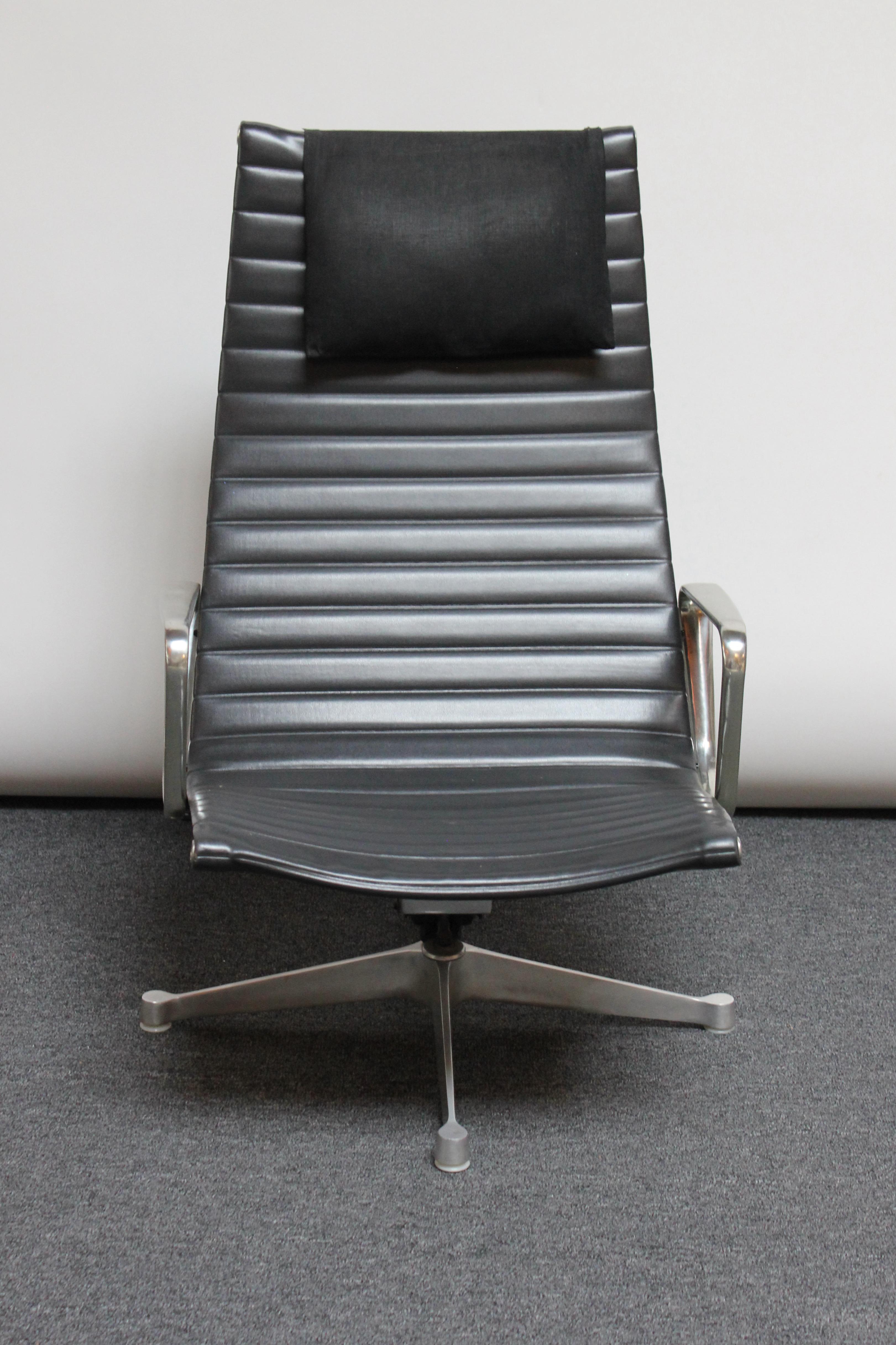 Early high-back lounge chair with swivel / tilt function designed by Charles and Ray Eames and manufactured by Herman Miller as part of the Aluminum Group collection. Composed of black channelled vinyl seat with linen cushion headrest on four-point