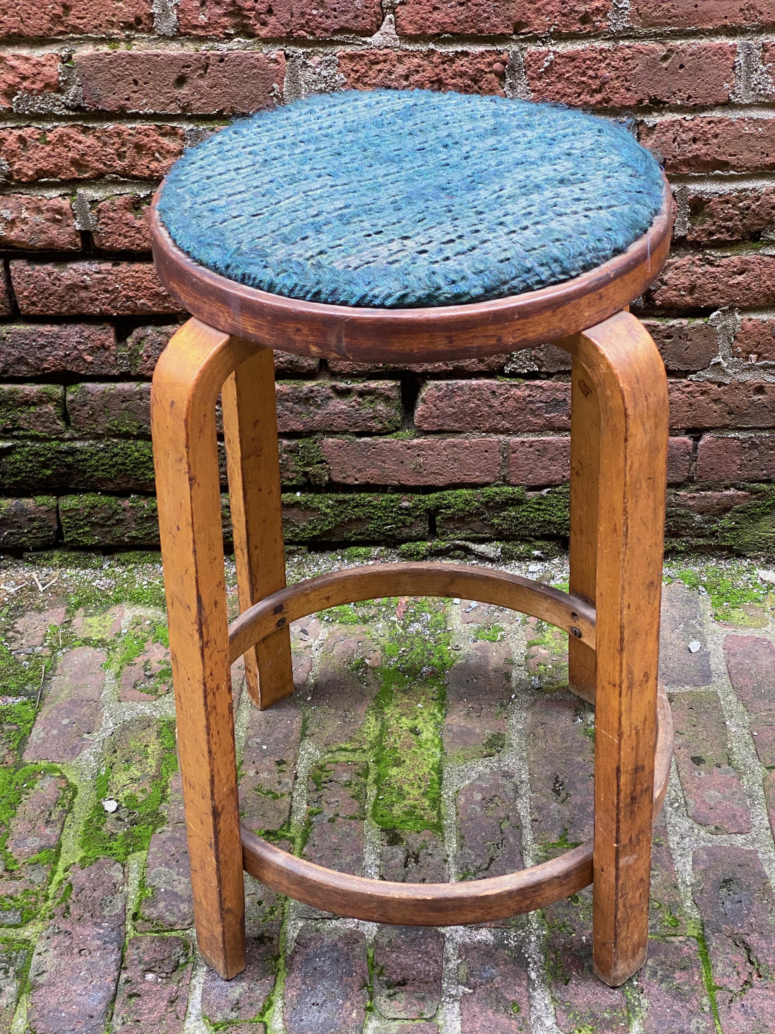 A very early example of Aalto's iconic use of laminated and bentwood. This stool has all the patina, wear and bruises of time and use, circa 1940-1950. Some screws are missing from round stretcher and the upholstered seat is tattered and worn.