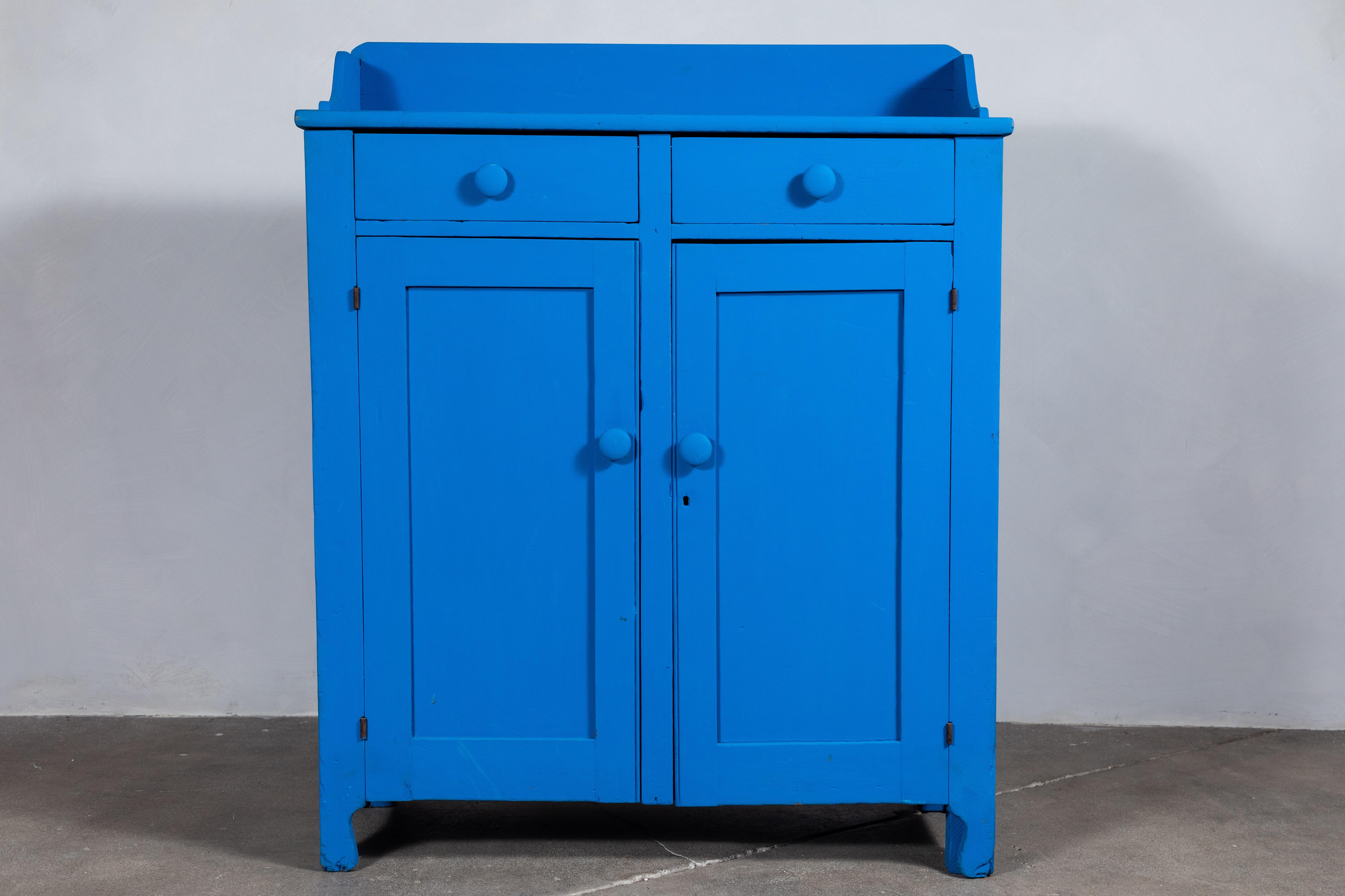 Early American jelly cabinet newly repainted in a vibrant blue. The jelly cabinet offers two top drawers with two lower doors.