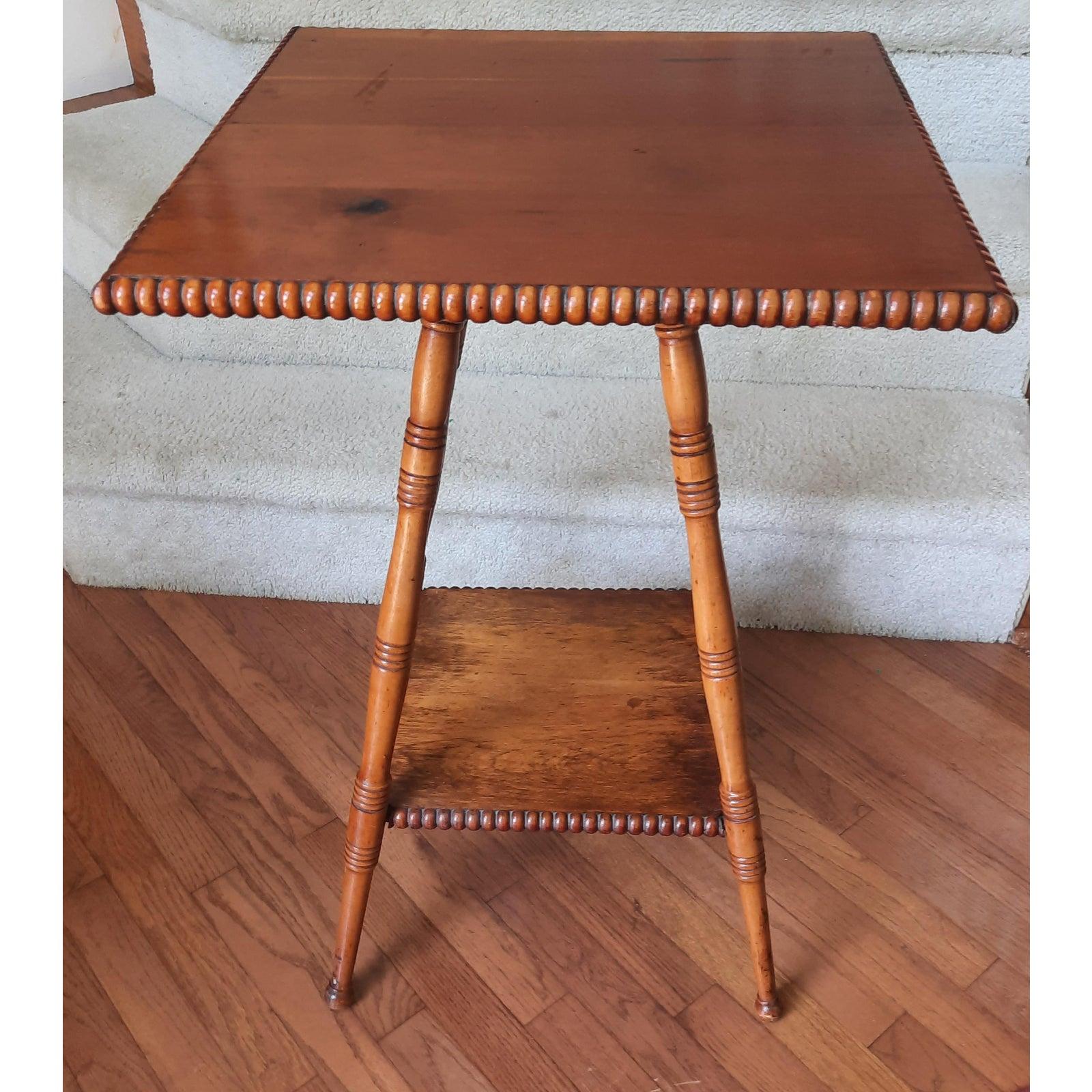 Two tier early American, occasional, parlor accent table. This American Classical style barley twist wooden side or occasional table features two-tiers including a large tabletop with smooth twisted edges. As well as a second smaller bottom tier