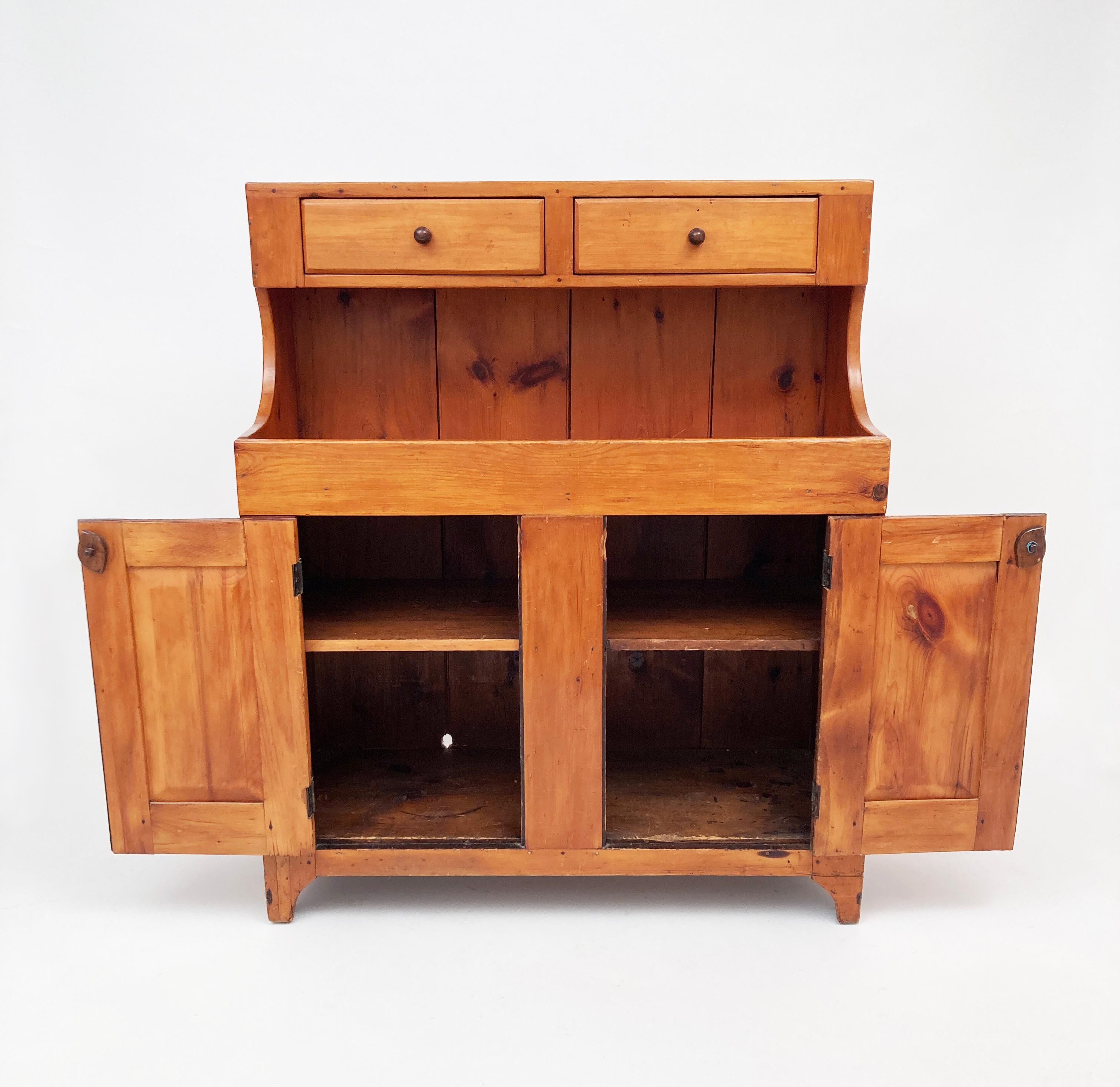 This very early American pine dry sink is a primitive beauty. The impressive craftsmanship that went into the construction of this piece has allowed it to stand the test of time. The entire piece is constructed and joined with hand chiseled dove