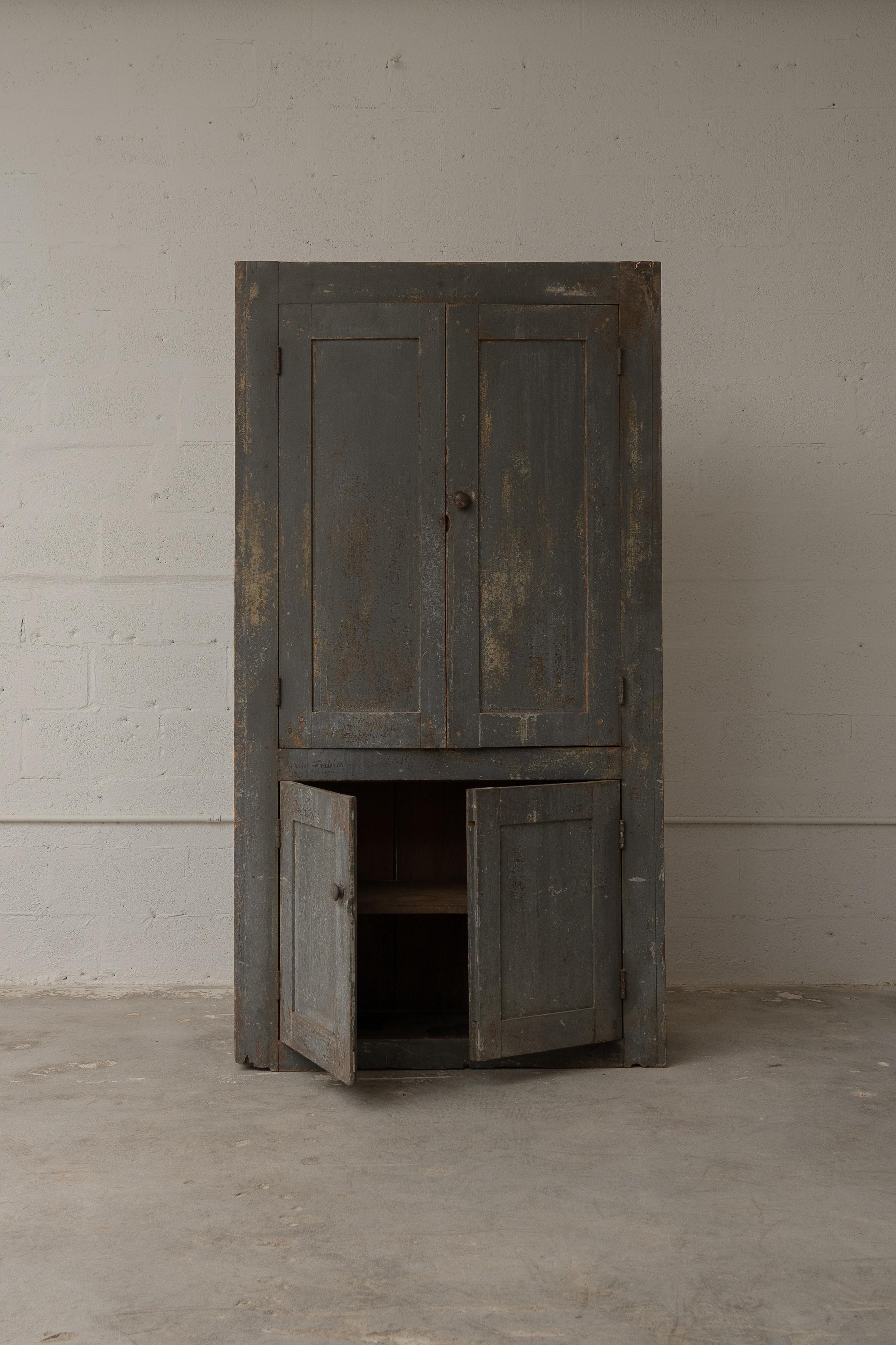 Une étonnante armoire américaine du XIXe siècle, dont la surface peinte d'origine est usée par le temps et dont la patine est magnifiquement altérée par les intempéries. Cette pièce présente des portes à panneaux classiques et des boutons en bois