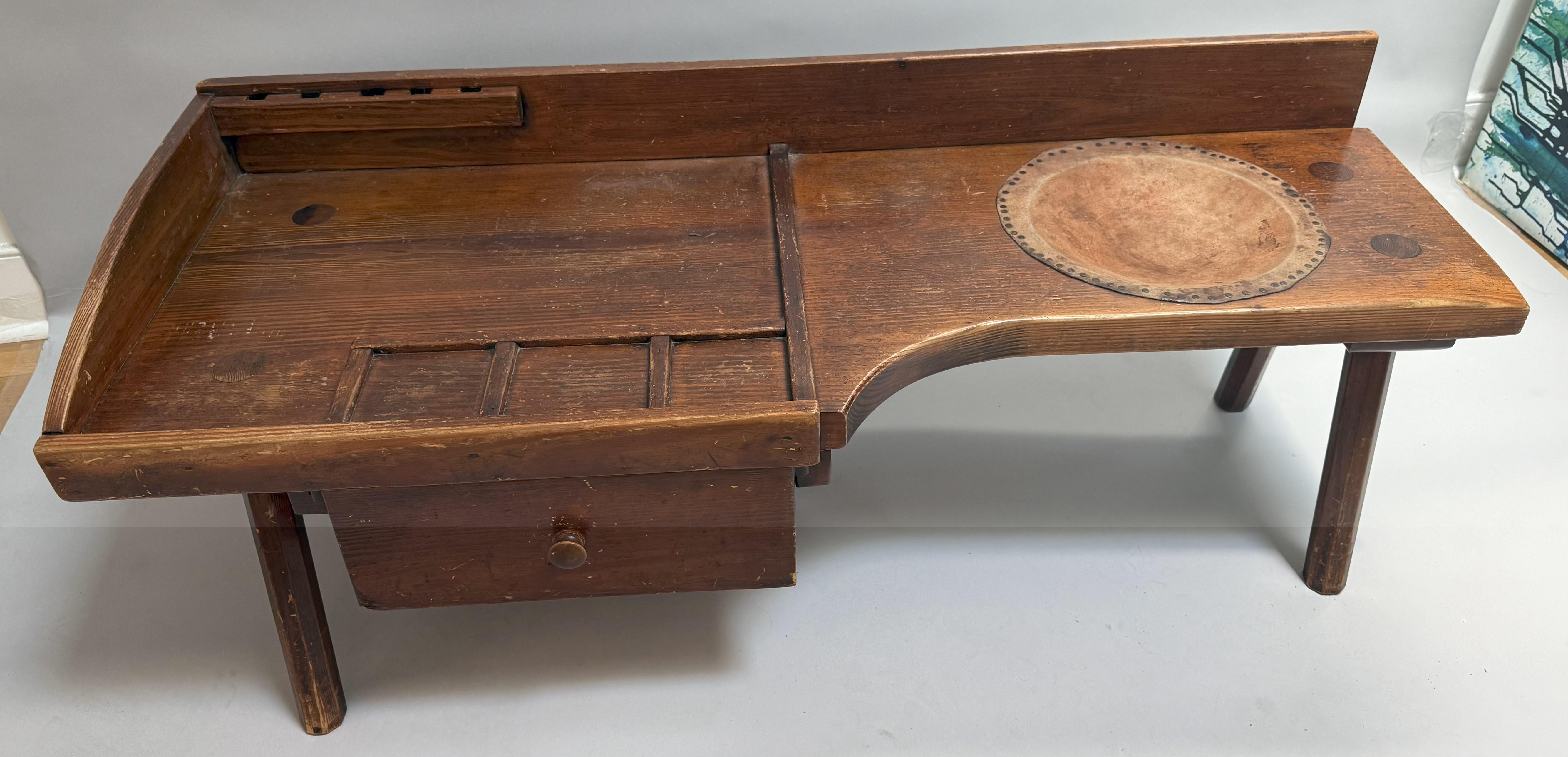 A soulful relic of American craftsmanship, this Early 20th-century cobbler's bench brings together form, function, and history in a singularly compelling form. Handcrafted in Virginia circa 1920, the piece is hewn from solid pine, its surface now
