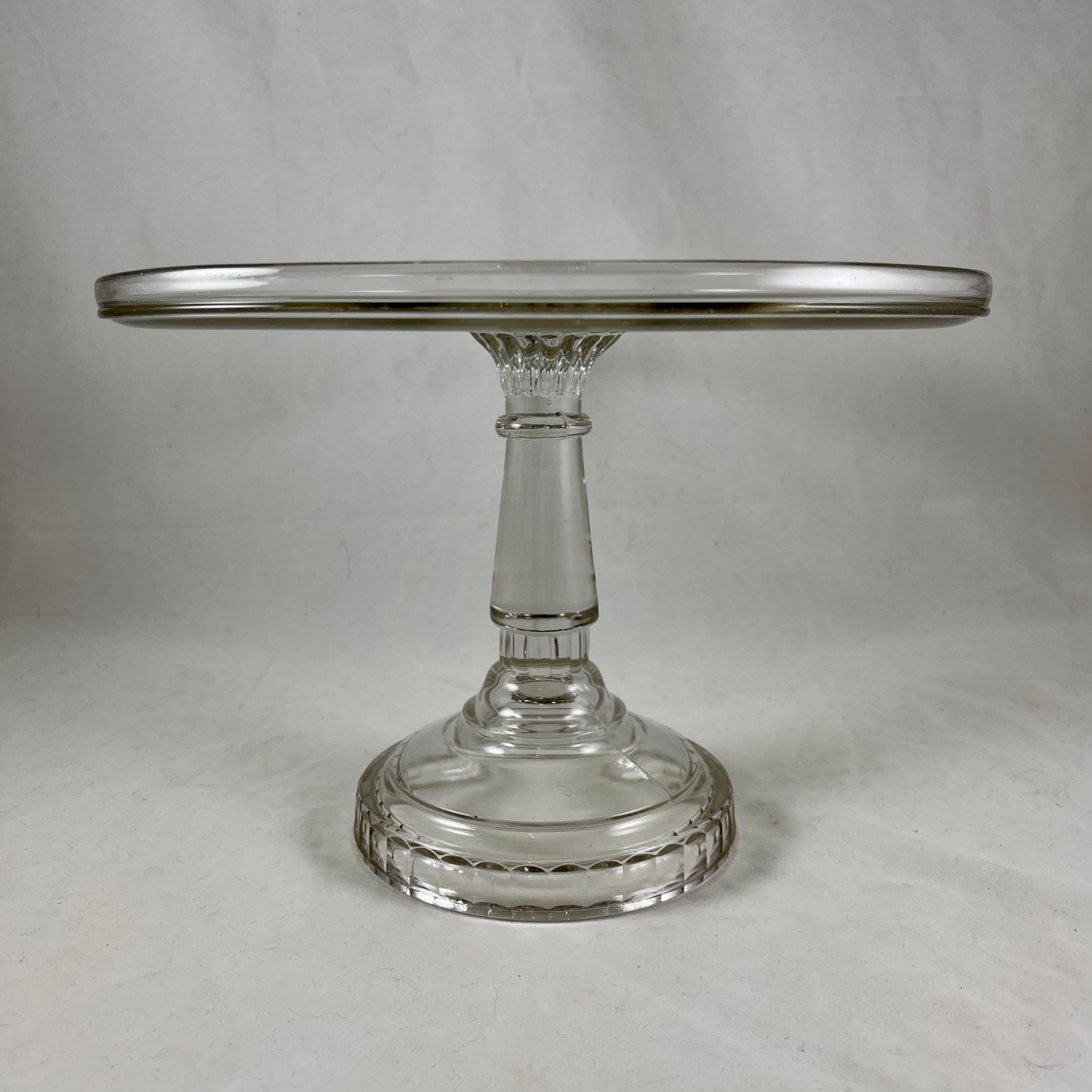 An EAPG, early American pressed glass cake stand, circa 1890-1900.

Made of nonflint, colorless molded glass, this large sized and heavy stand has a thick paneled stem. The footing has a paneled stem, the plate has a raised border.

7.75 inches