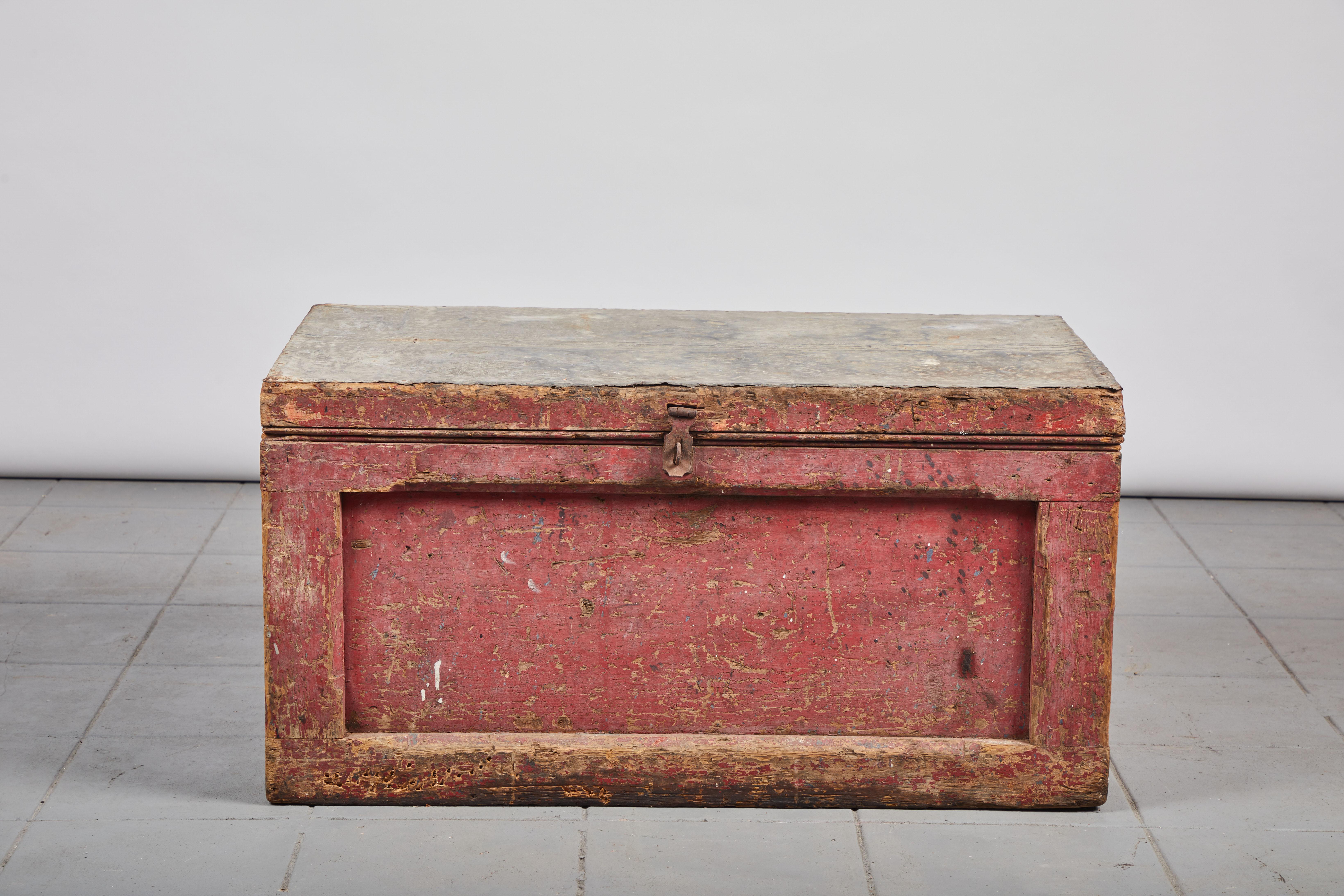 Red colored early American rustic trunk with zinc top.