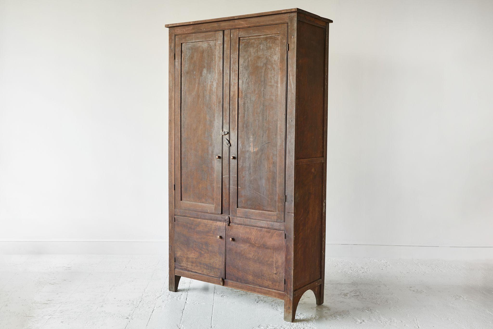 Early American rustic walnut wardrobe cabinet with four doors. The wardrobe offers original details and stain. The interior consists of one side with horizontal shelves and the side is open.