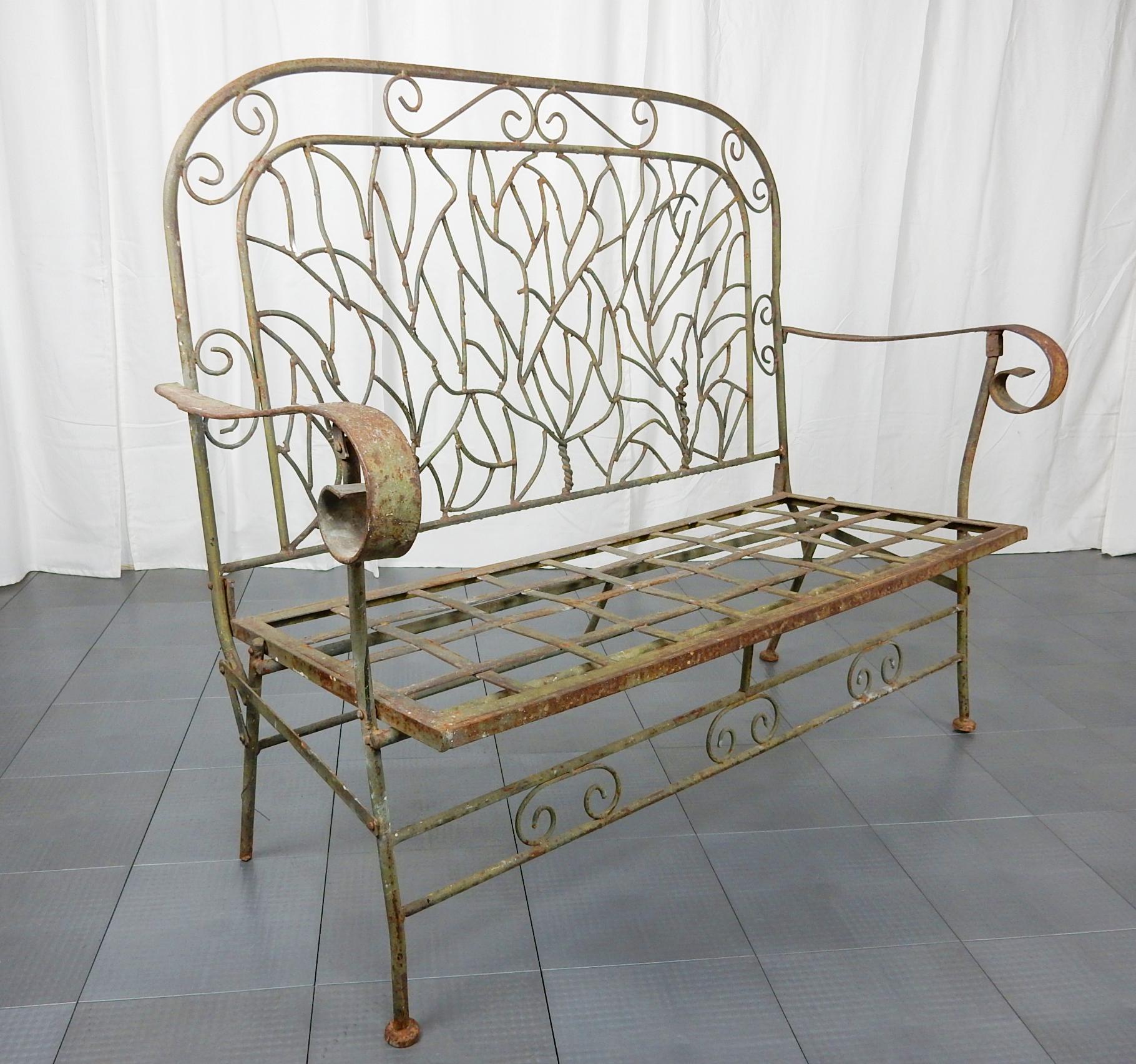 Artfully sculpted iron folding garden bench circa 1930s
From an Arts & Crafts bungalow in Pasadena California.
Abstract TWIG design backrest. Large curly armrests.
Old green painted surface. Folds on half at center.
Formed of solid iron. Not