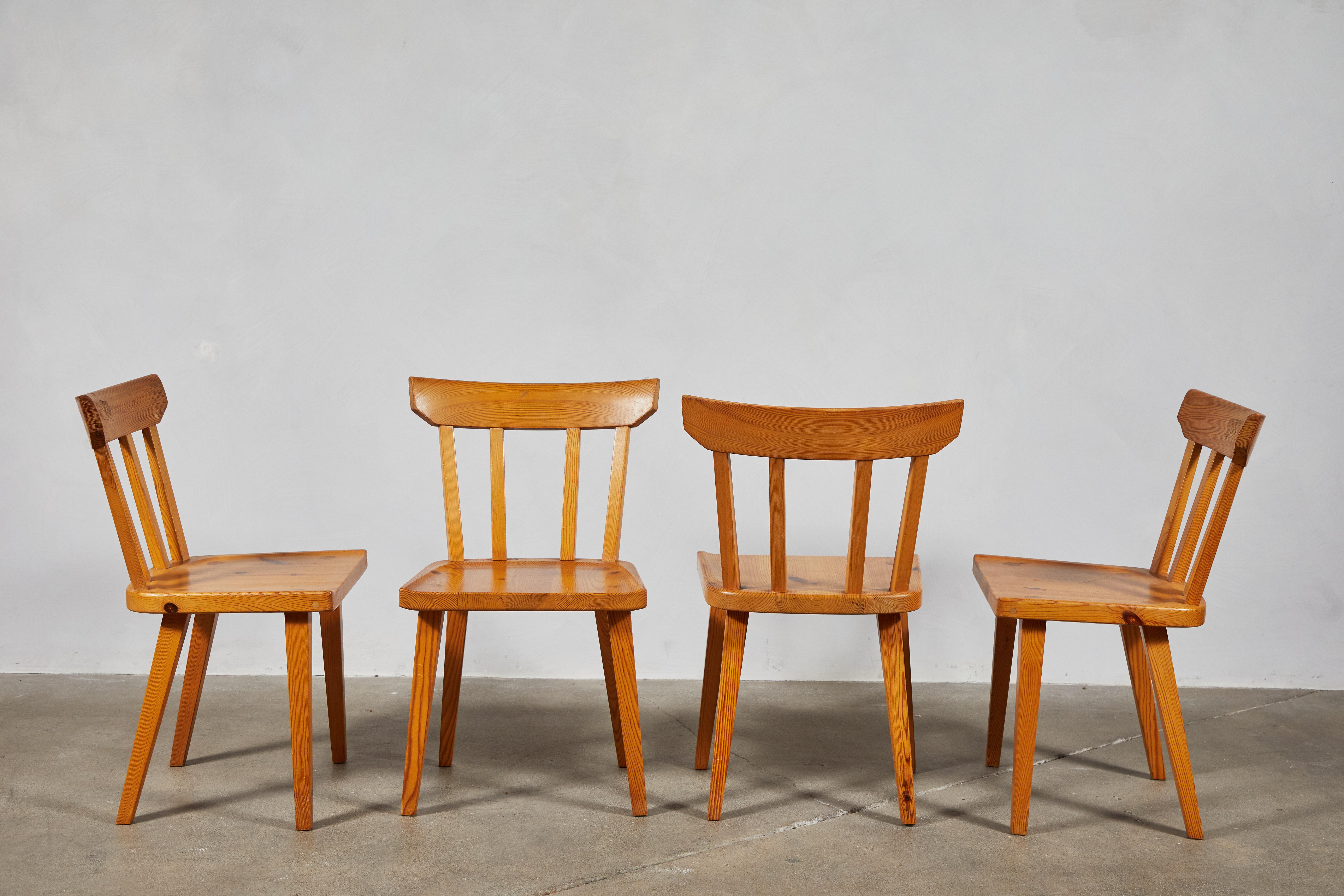 Mid-Century set of four pine dining chairs with spindle backs. The chairs offer simple construction and clean lines.