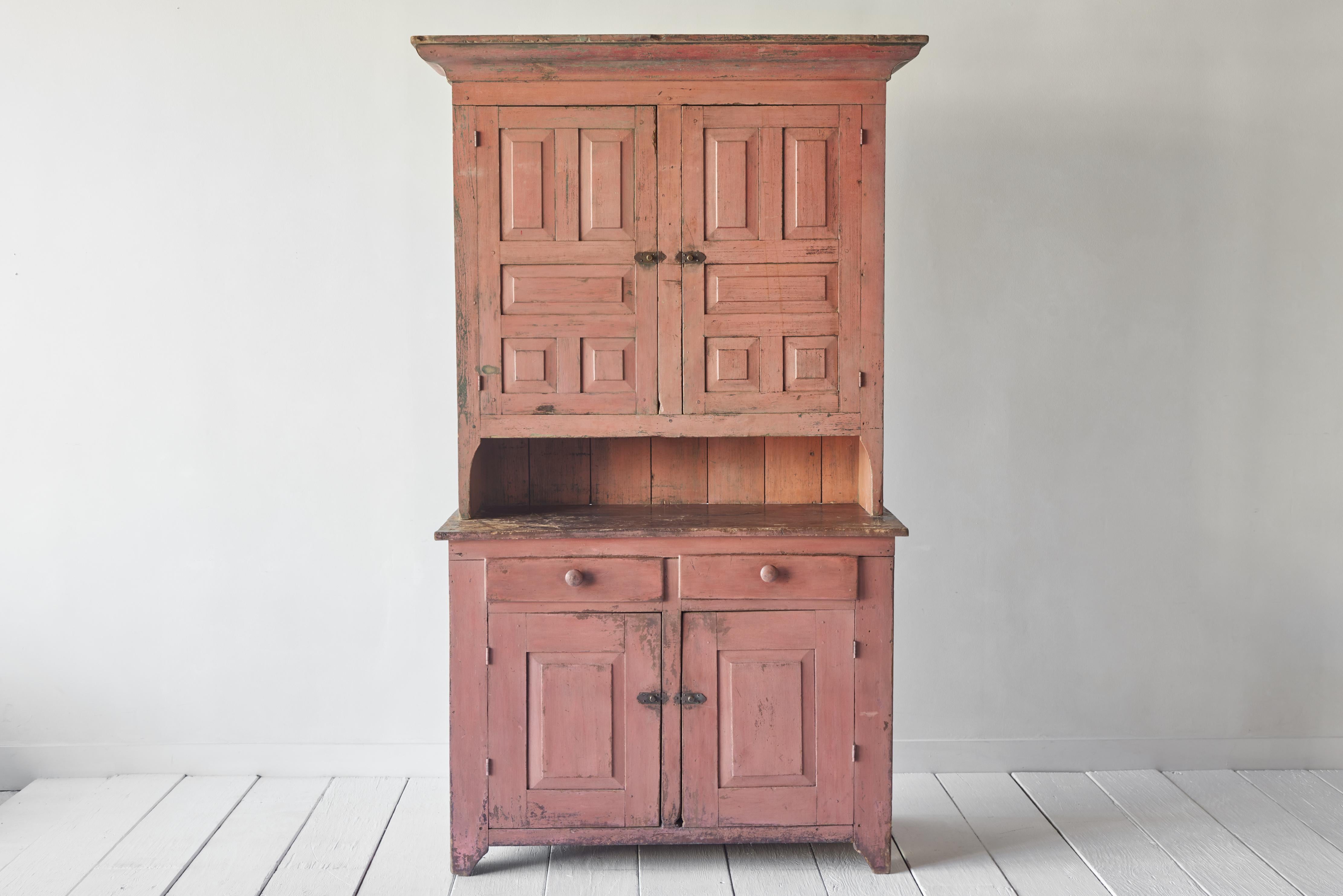 Early American salmon painted step back cupboard. Oversize cabinet with ample storage. Cupboard is in good structural condition, with visible surface wear consistent with age and use.
 