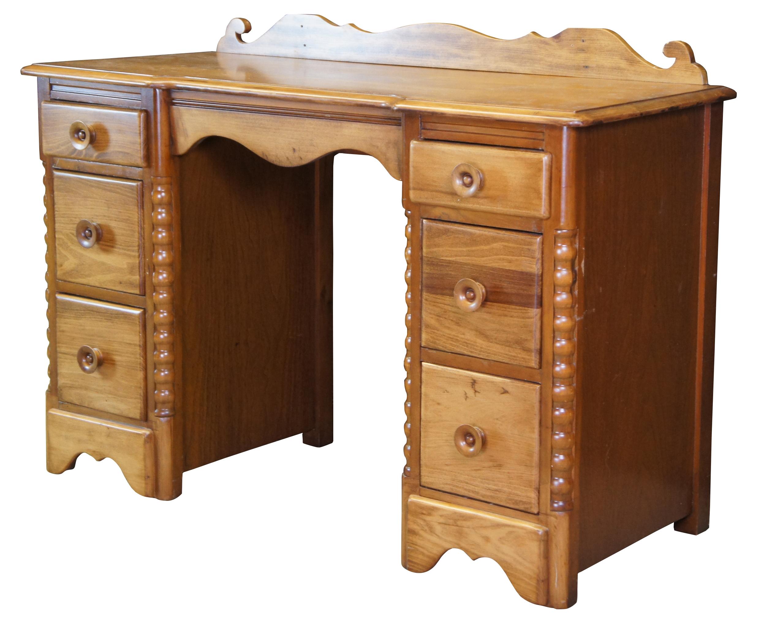 Early American style kneehole desk or vanity, circa 1960s. Made of oak featuring turned and ribbed accents with scrolled backsplash and six drawers. 

Measures: 46
