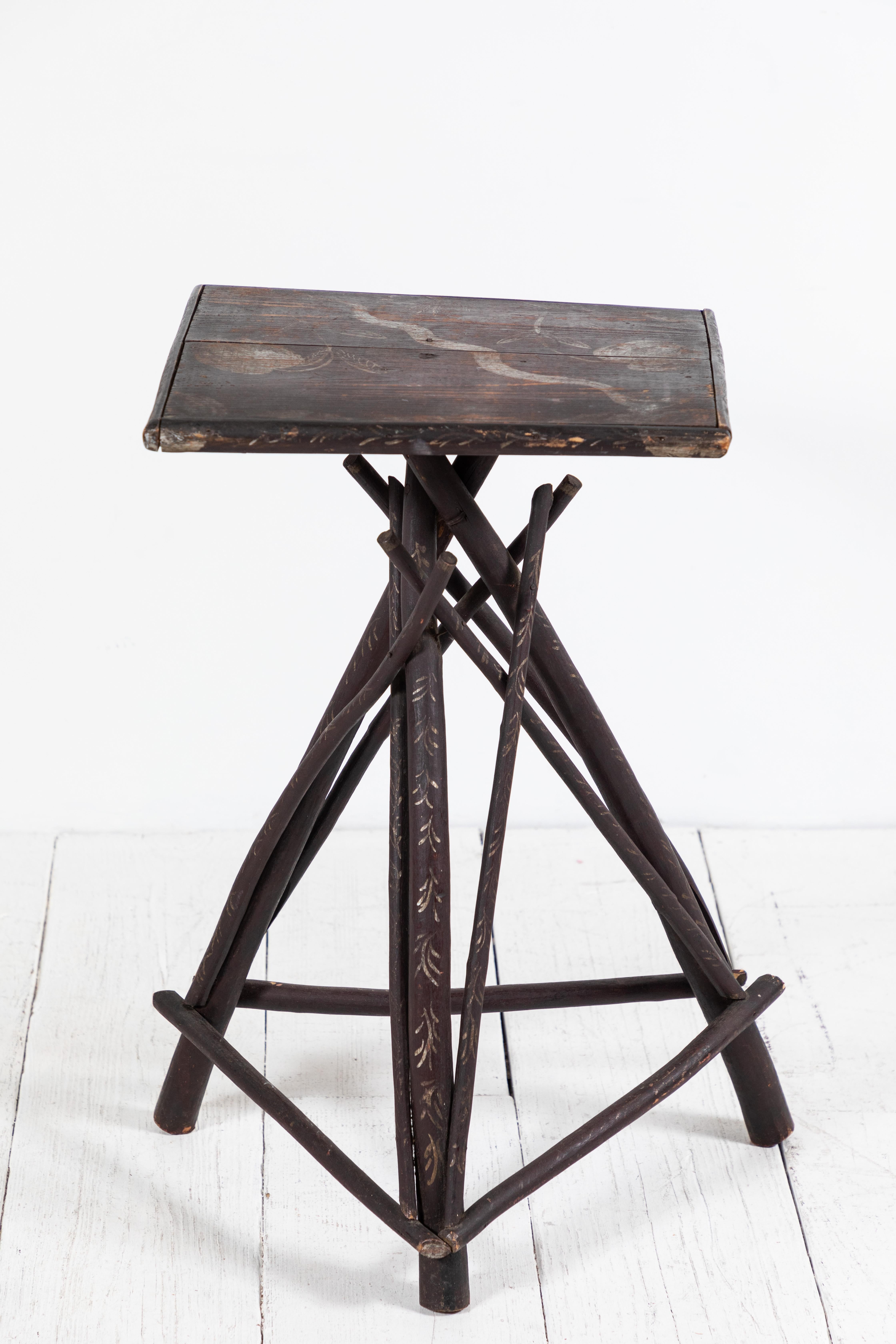 Rustic early American Adirondack style tall side table with stained twig legs and hand painted stenciled top.