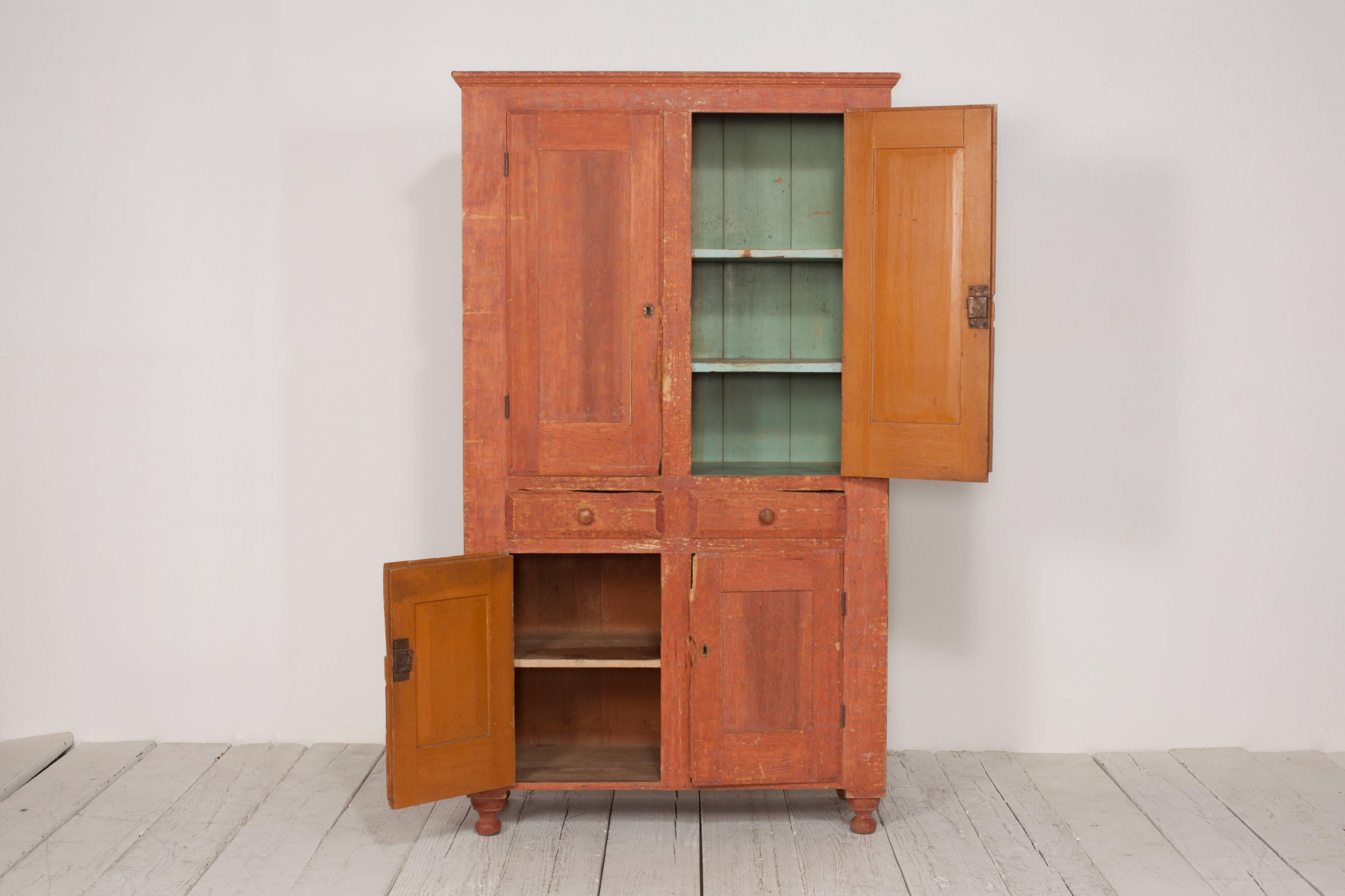 Early American terra cotta stained cabinet with four doors and two drawers. Interior is painted the original blue accent details.