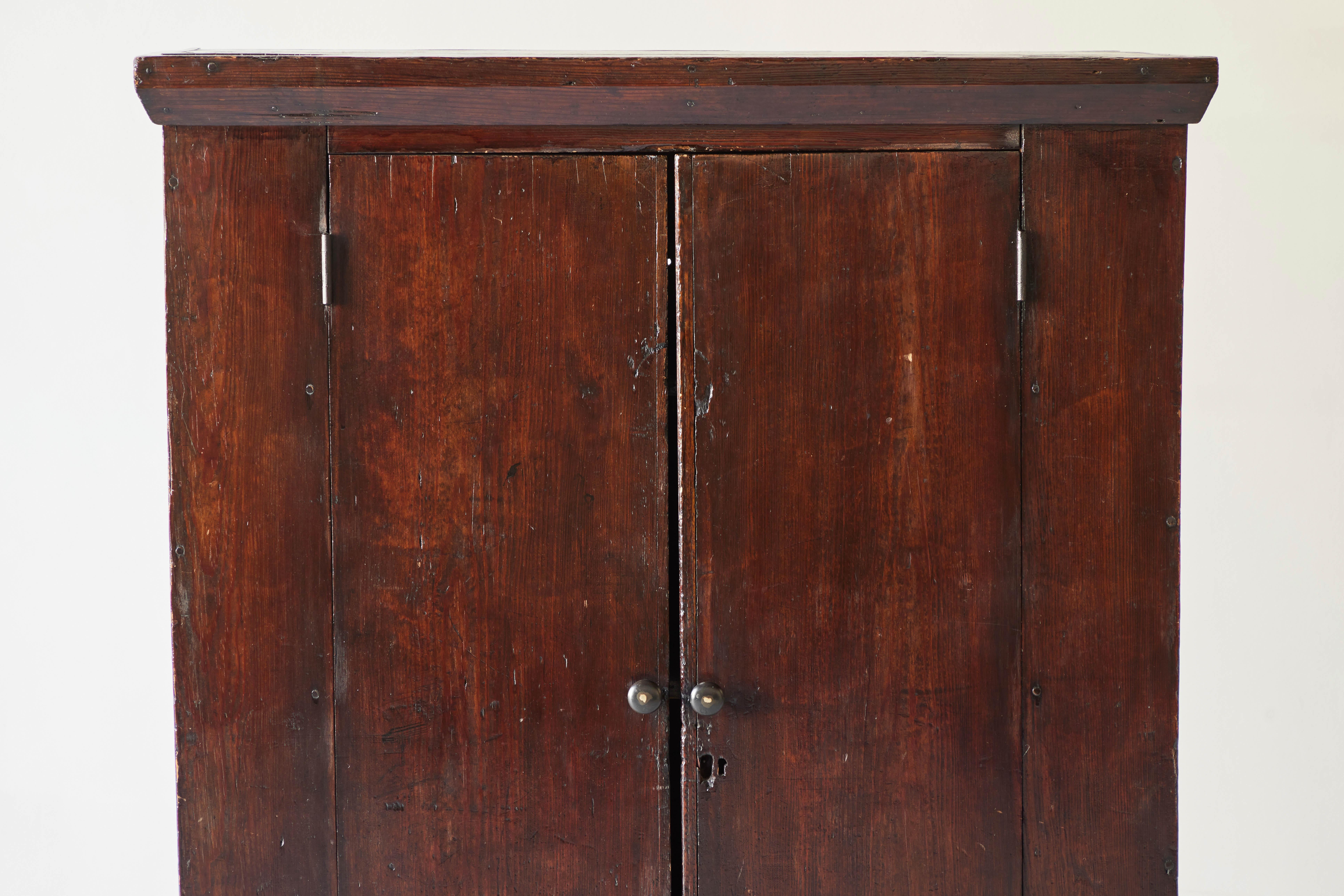 This Early American cabinet is a Classic example of Early American furniture with legs and feet that are simply downward extensions of the simplistic rectangular style. This piece can be classified as in the style of Shaker furniture with its