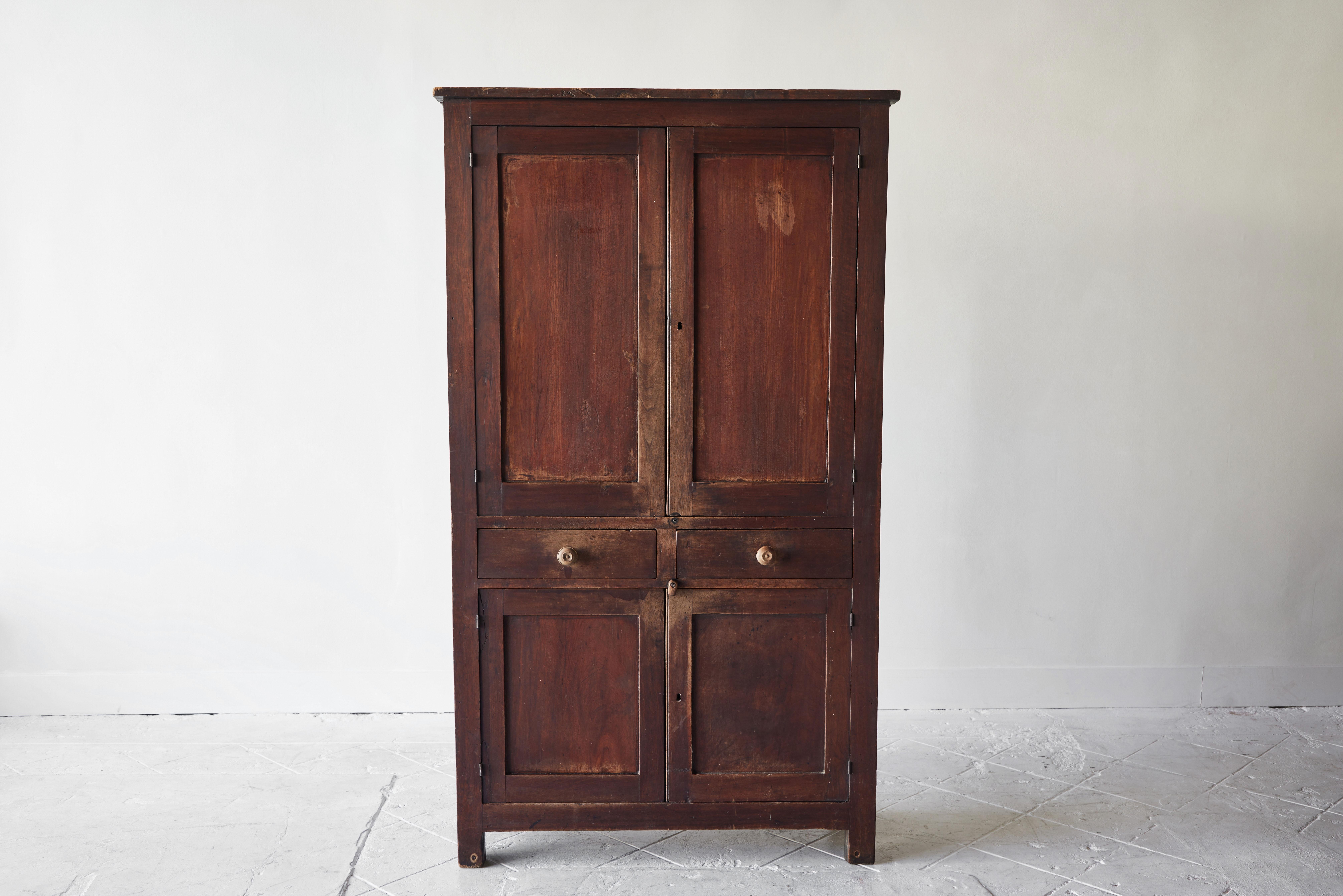 This early American walnut cupboard is a classic example of early American furniture with legs and feet that are simply downward extensions of the simplistic rectangular style. This piece can be classified as in the style of Shaker furniture with