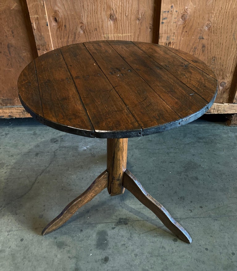 This early American wood side table acts as a taller sofa accompaniment or smaller cafe table with rich patina and carved wooden base.