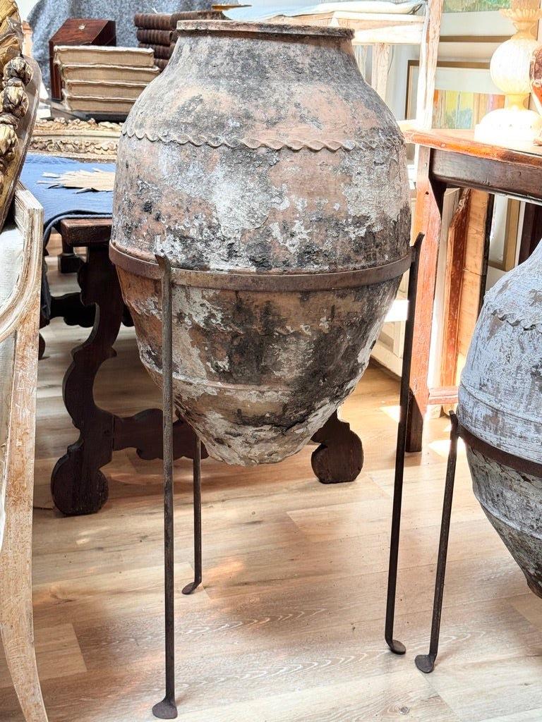 An early Anatolian terracotta storage jar, likely 18th century or earlier, with a tapered base, wavy applied collar, and richly weathered surface. Mineral accretions suggest prolonged outdoor or coastal exposure. Once used for oil or grain, now