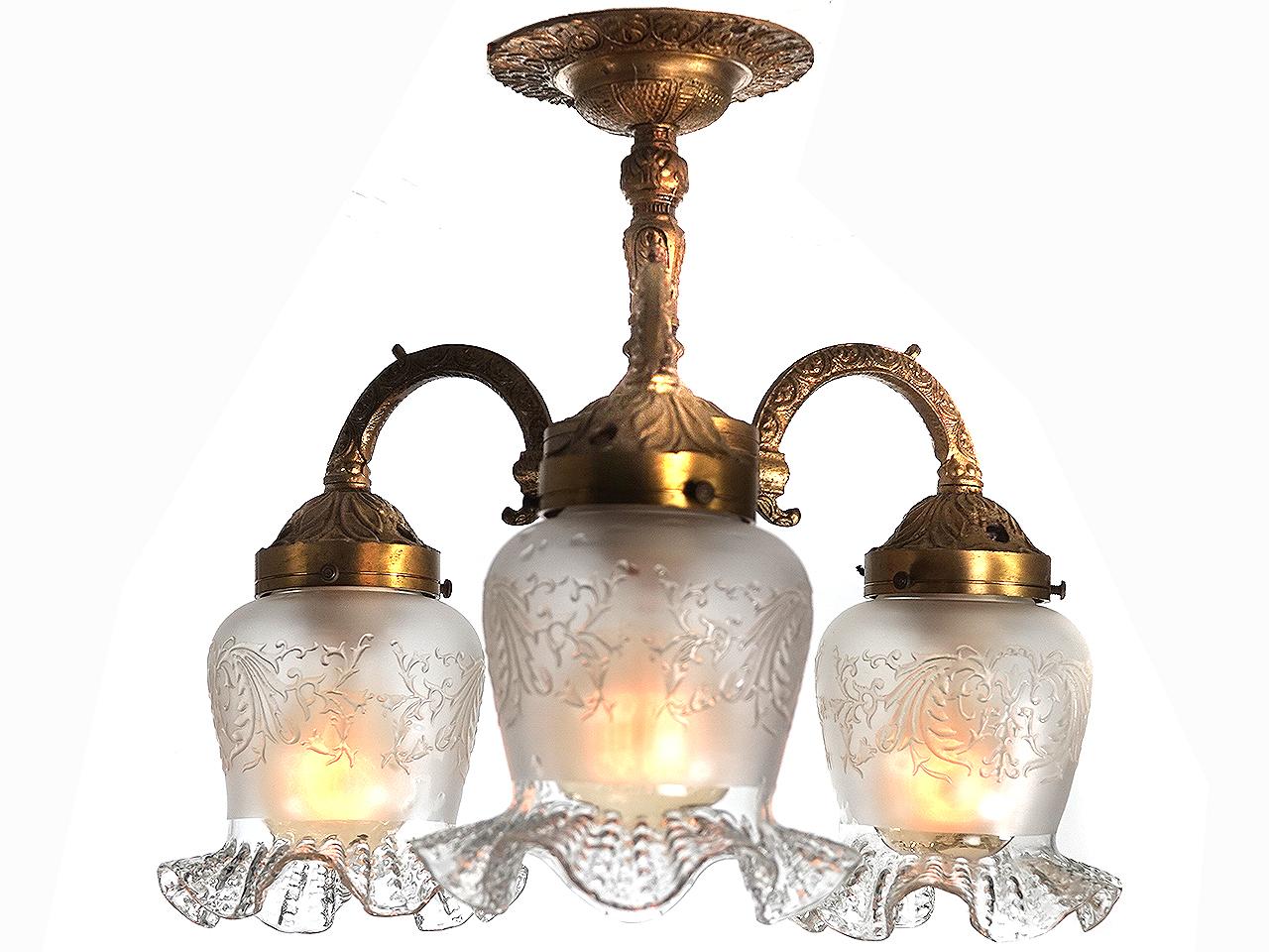 From the look and finish I'm guessing this ceiling flush mount could be French. The bronze has decorative detail covering most of the lamp. The floral glass shades are very delicate, hand blown with etched details. This is a nice early and elegant