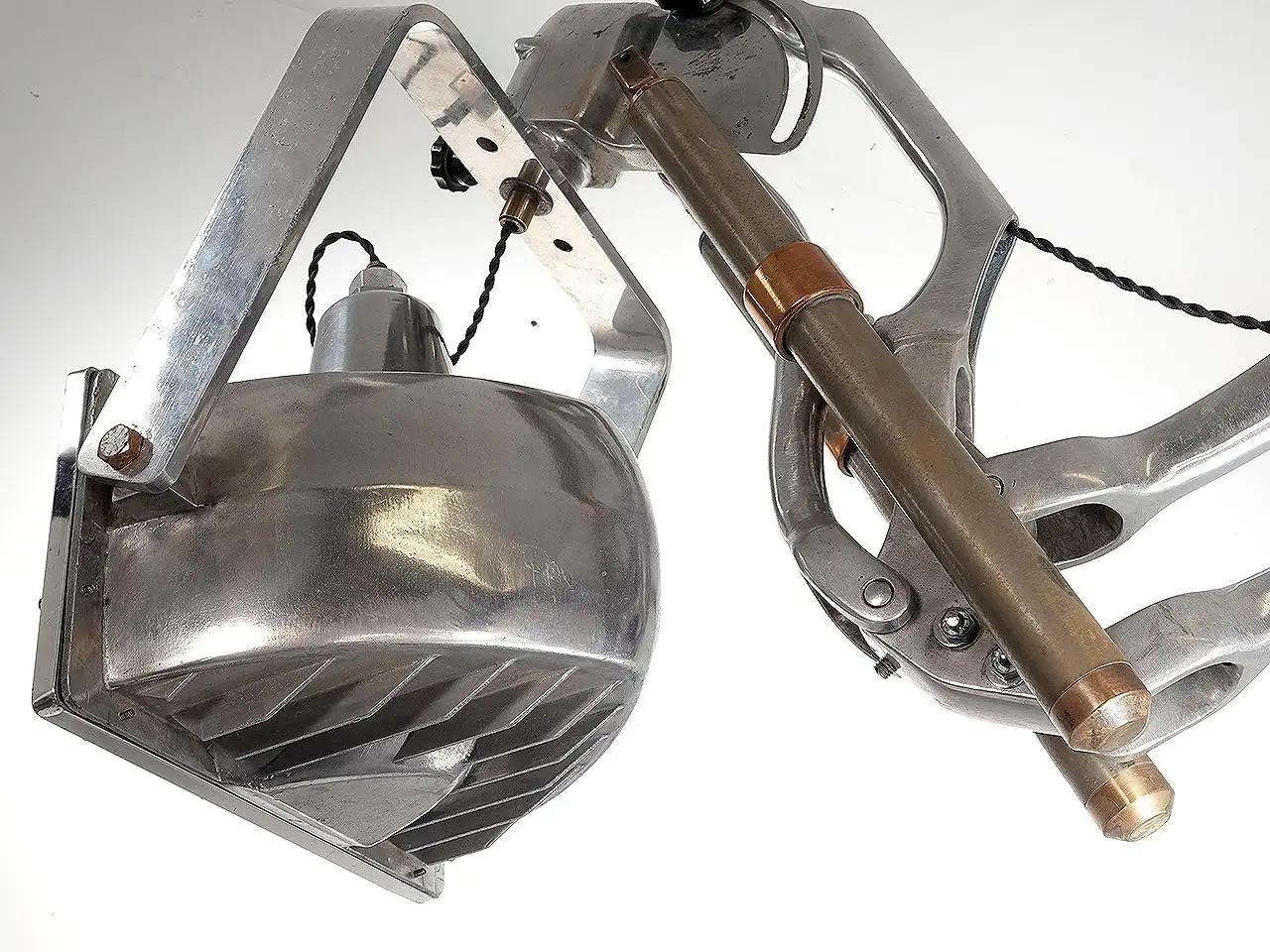 This impressive lamp started life as a 1930s X-ray machine. The head Was an aluminum spot lite that we fit to the heavy duty arm. The articulated arm and lamp were polished to a bright finish. The arm extends to over 5 foot and folds to the wall.