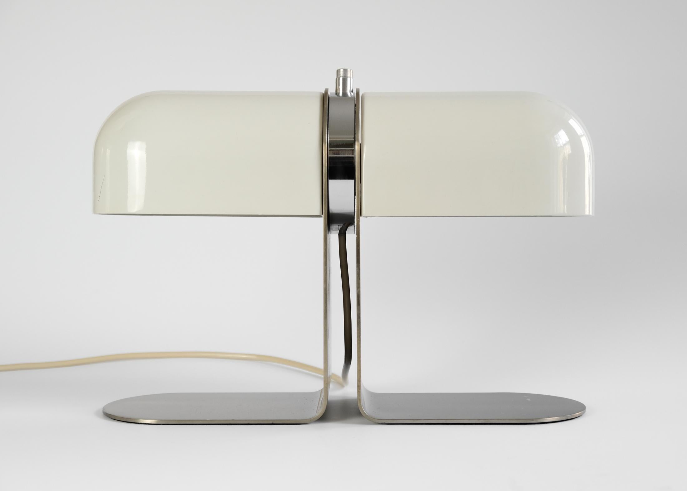 For sale is an early example of this rare table lamp by André Ricard, for METALARTE, Spain, circa the early 1970s.

The lamp consists of a rotating head comprised of a circular chrome block, with a mounted switch and flanked by two metal shades, all