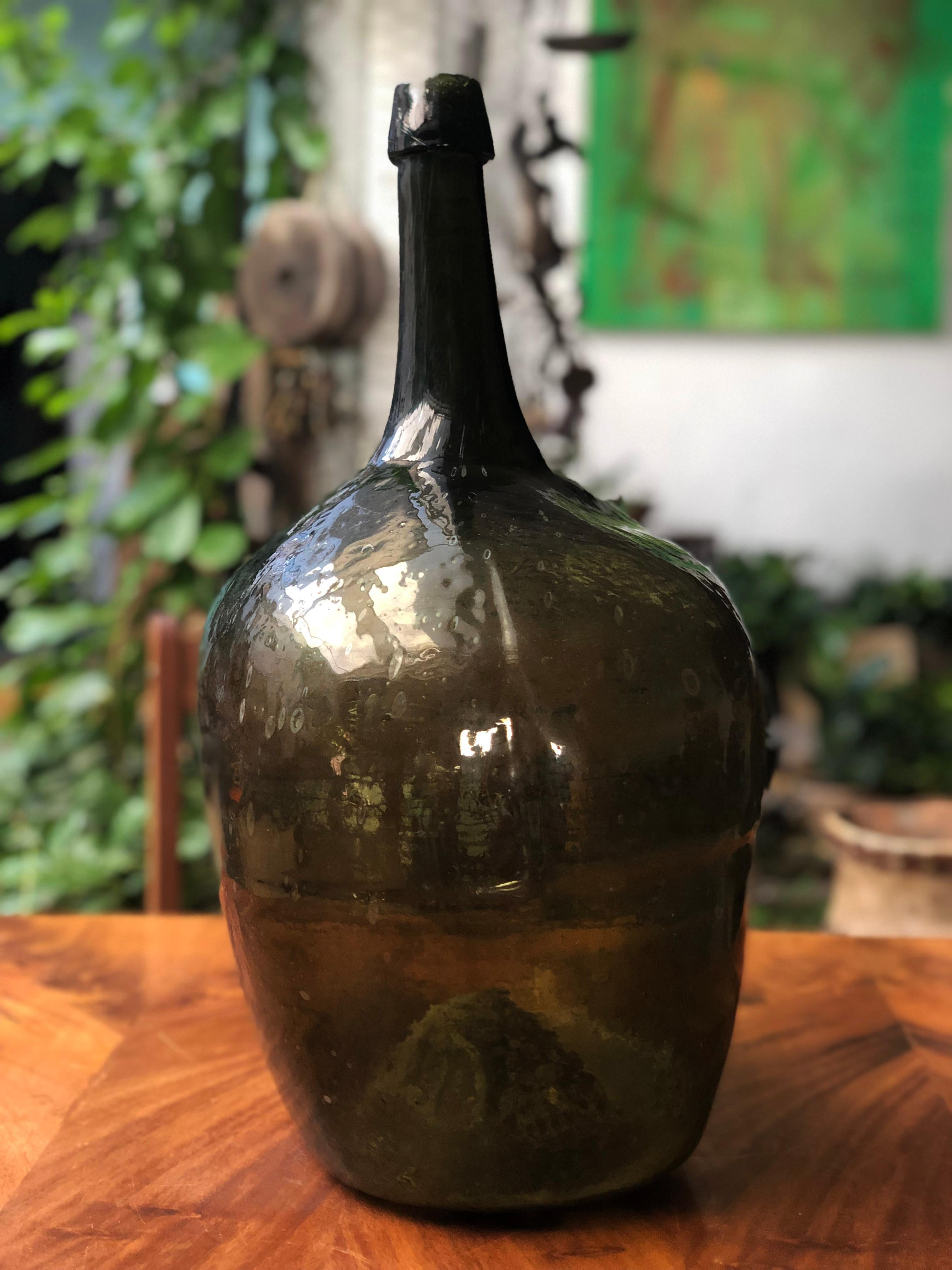 Late 19th century blown glass dark green demijohn bottle with a beautiful bold irregular sculptural form and a very deep dished pontil. Dating anywhere from the late 18th-early part of the 19th century.