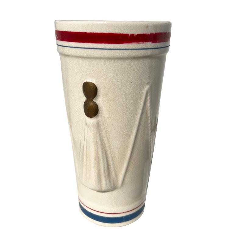 An early ceramic drum motif vase by Hull Pottery. This tall painted vase is made of ceramic and features a raised design around the body that resembles a drum. Raised rope djembes stretch vertically from top to bottom and are decorated with raised