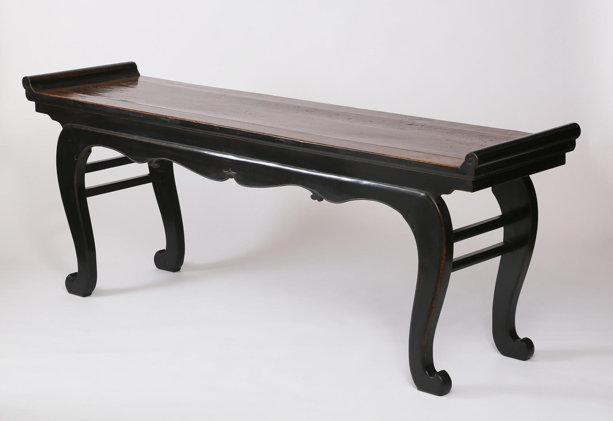 The altar table with everted flanges covered in rich black lacquer, the lacquer on the top worn out, exposing the beautiful grain, the top above cusped curvilinear foliage aprons carved with a beading, supported on cabriole legs, reinforced by