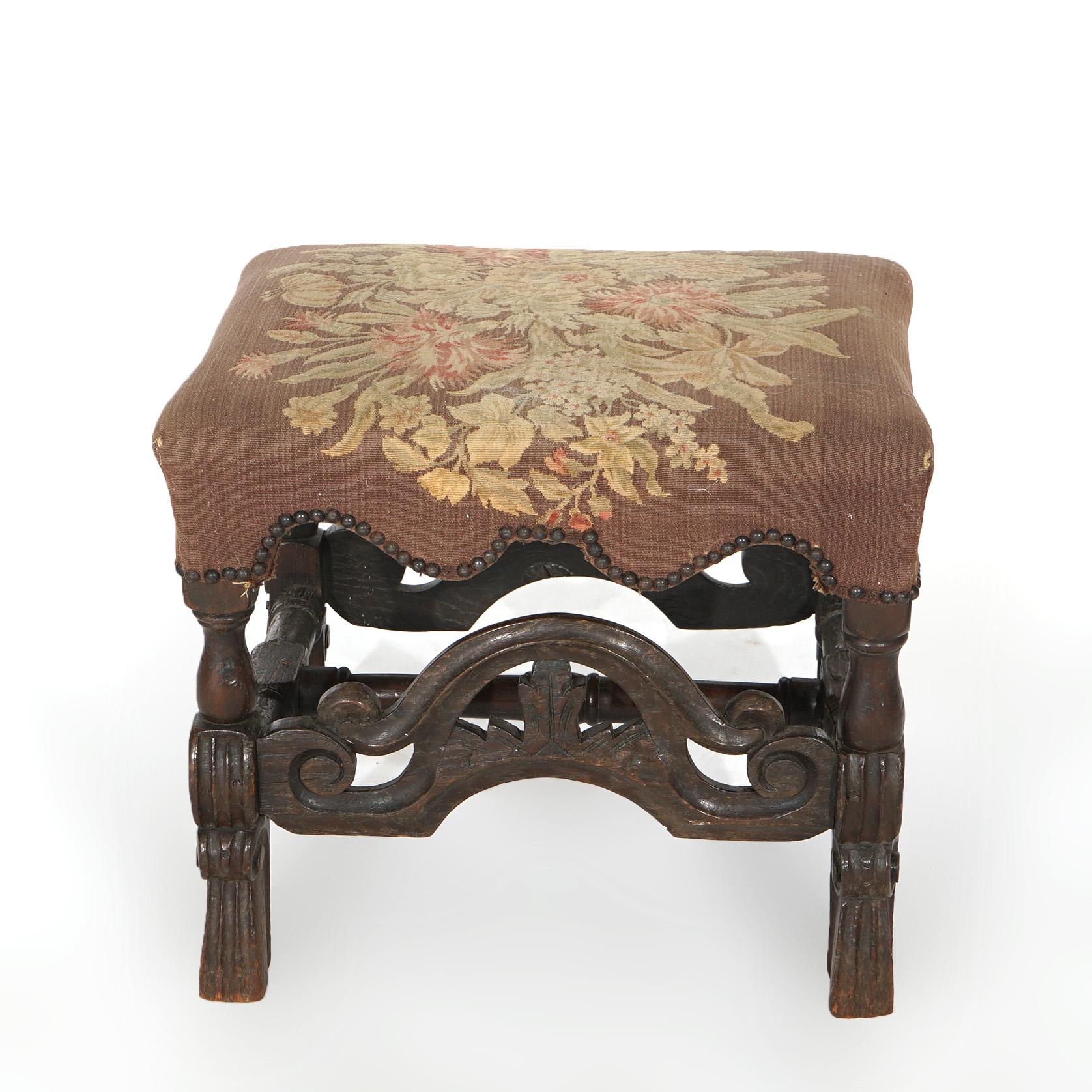 An early antique English bench offers floral needlepoint upholstered seat over walnut base having carved foliate, scroll and reeded elements, c1690

Measures - 17