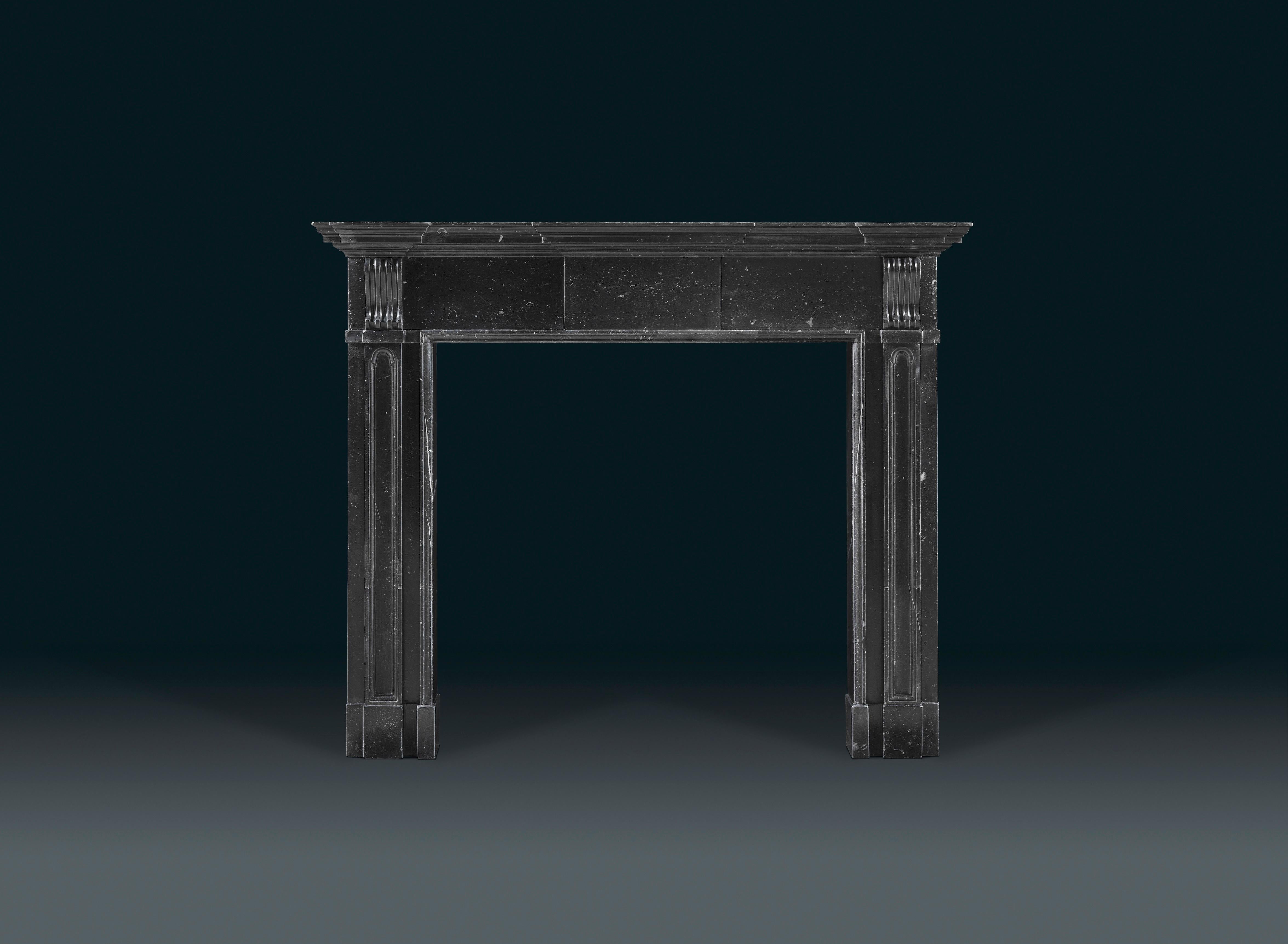 An early Architectural Palladian, Irish chimneypiece of black Kilkenny marble, with moulded tiered shelf and plain frieze centered with an uncarved tablet. The pilaster jambs incised with rounded arched decoration, each capped with scrolling