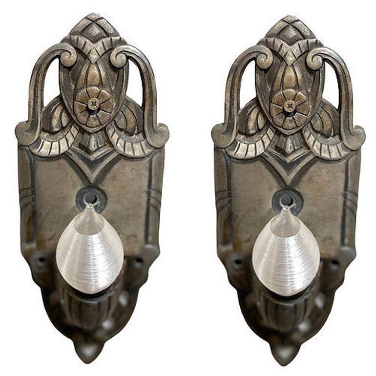 Coppia di appliques in alluminio lavorato in stile Art Déco con curve aggraziate e linee geometriche con motivi floreali al centro della piastra posteriore, che conferiscono un design elegante e moderno.

Dimensioni: Altezza: 10