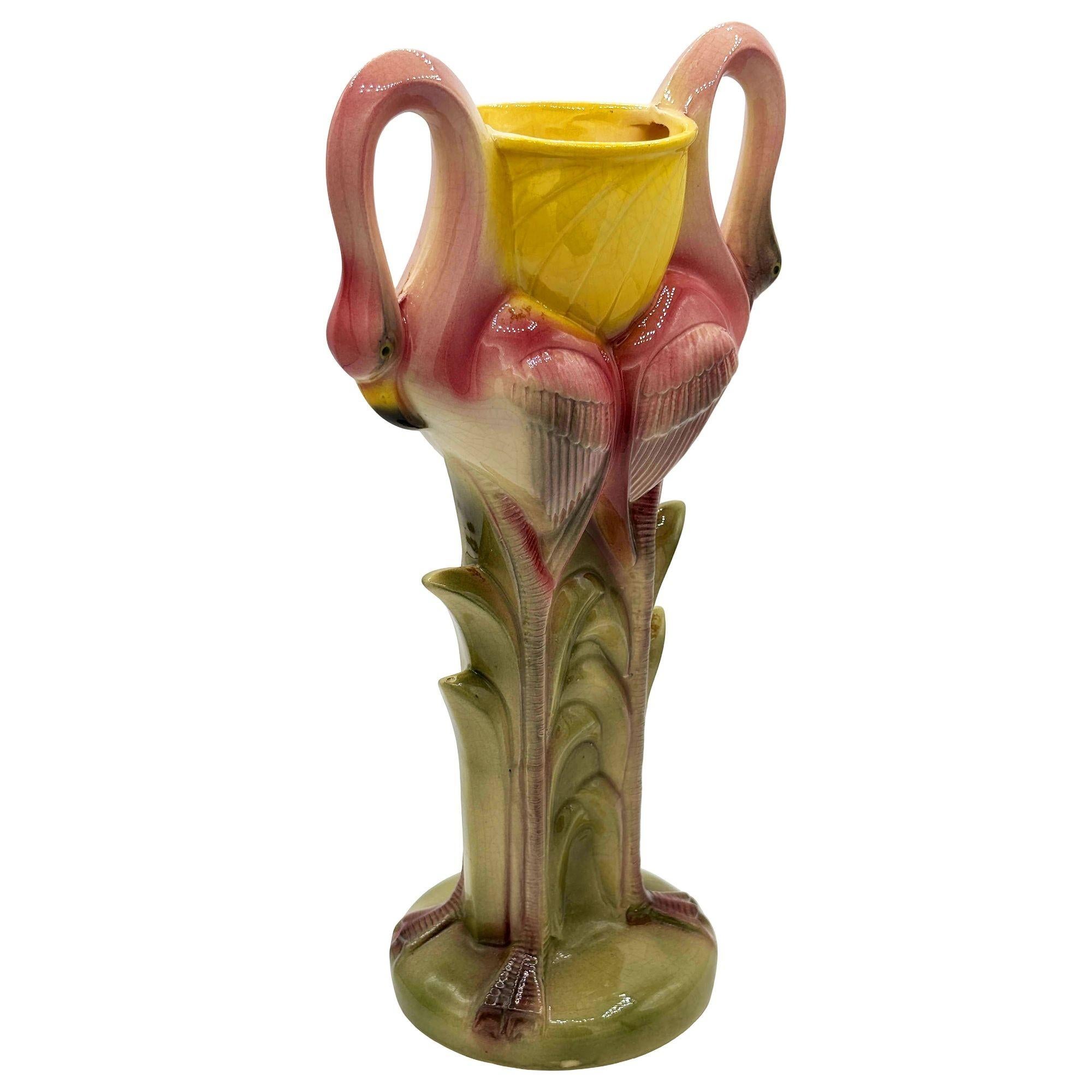 Vaso da fiori in ceramica rosa, giallo e verde a forma di fenicottero della California Pottery. Il vaso presenta una coppia di fenicotteri rosa splendidamente dettagliata che si blocca su un campo erboso verde e rigoglioso. La finitura lucida mette