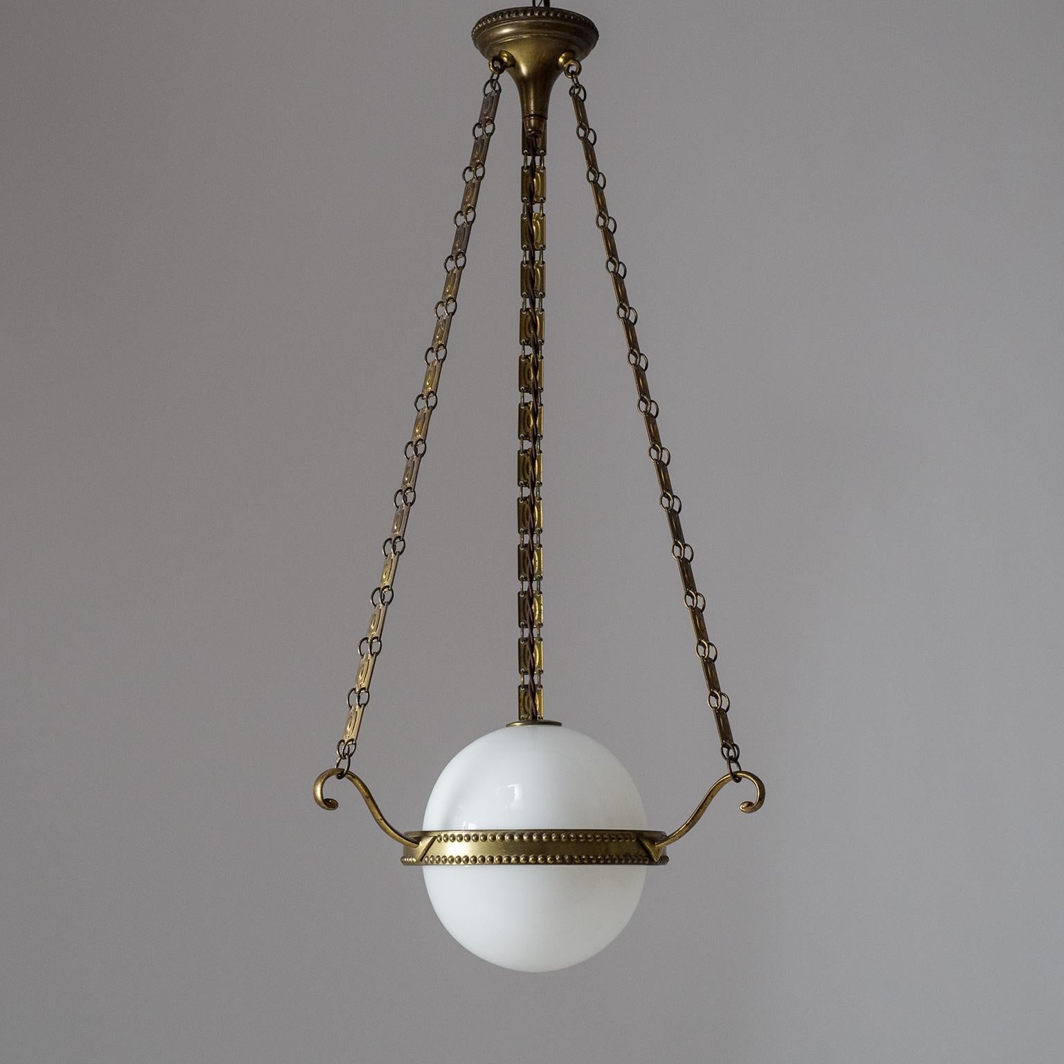 Splendid early 20th century Austrian brass and glass pendant. Intricately styled brass hardware suspended by three unique brass chains with a blown and cased glass diffuser appearing to float in the center. Wonderful original condition with a lovely