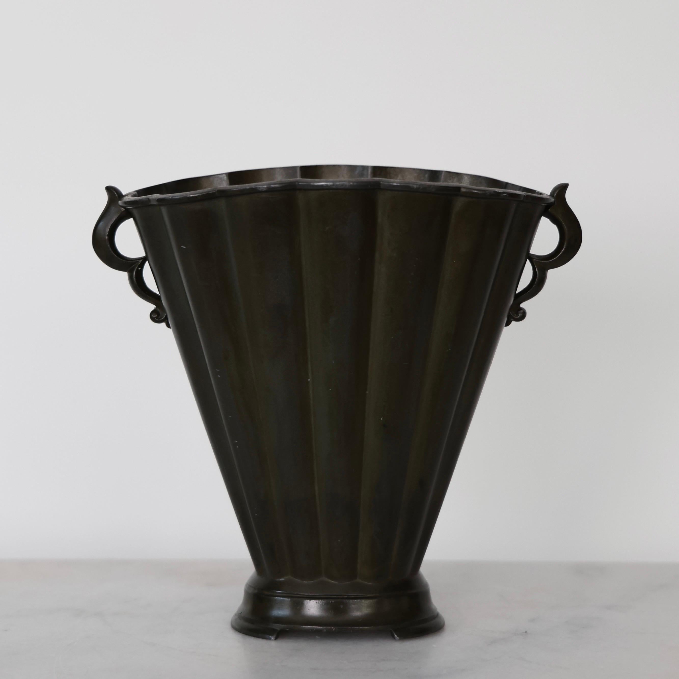 Vaso precoce disegnato da Just Andersen negli anni Venti. Un pezzo pregiato per una casa raffinata.

* Un vaso di metallo a forma di ventaglio con linee verticali e anse
* Designer: Just Andersen
* Model No: D20
* Anno: 1918-1926
* Condizioni: Buone