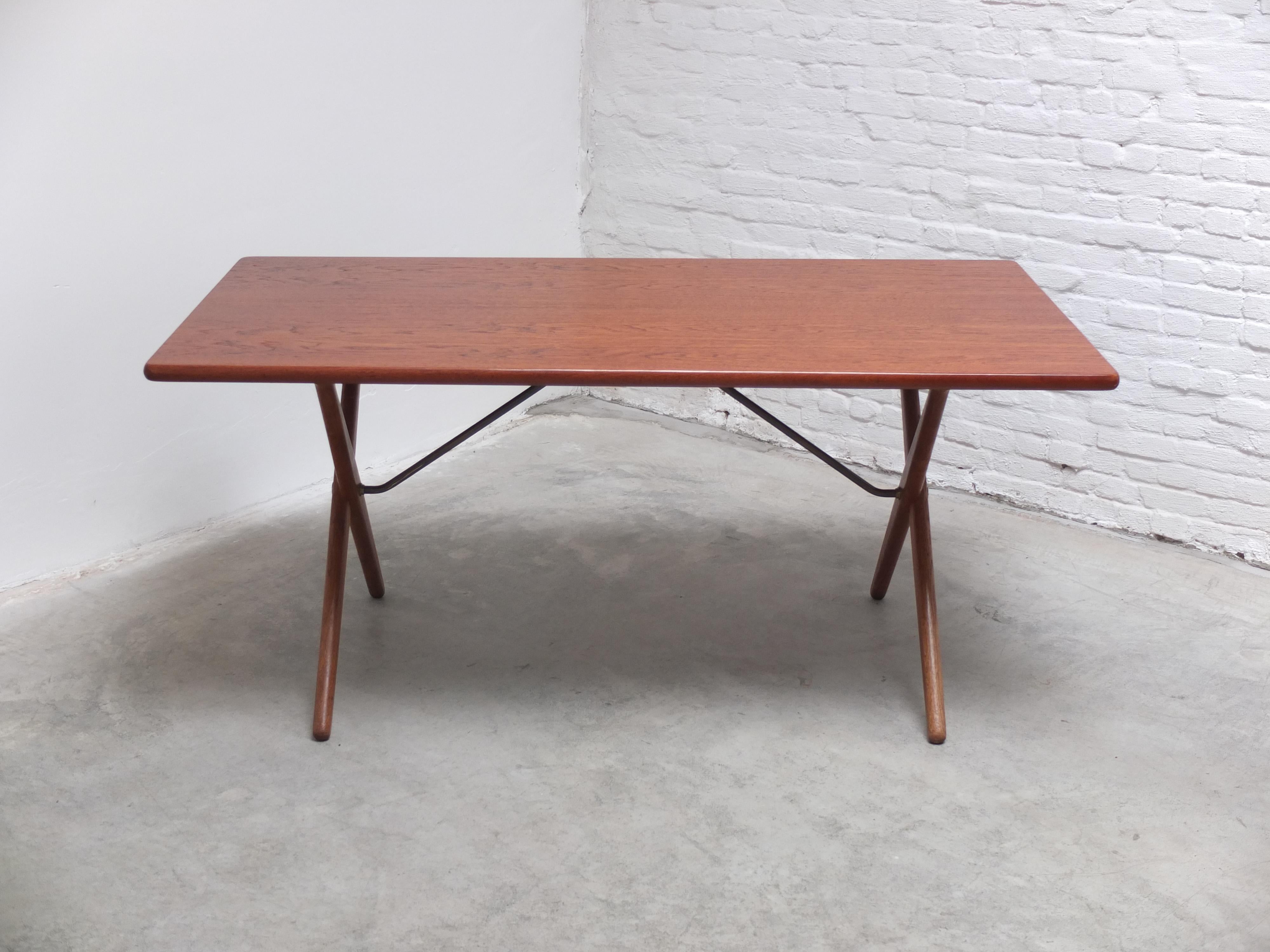 Fantastischer Esstisch 'AT 303', entworfen von Hans Wegner im Jahr 1955. Dieser so genannte Quertisch hat eine Platte aus Teakholz und Beine aus massiver Eiche mit einer Stange aus Messing und kann auch als Schreibtisch verwendet werden. Produziert