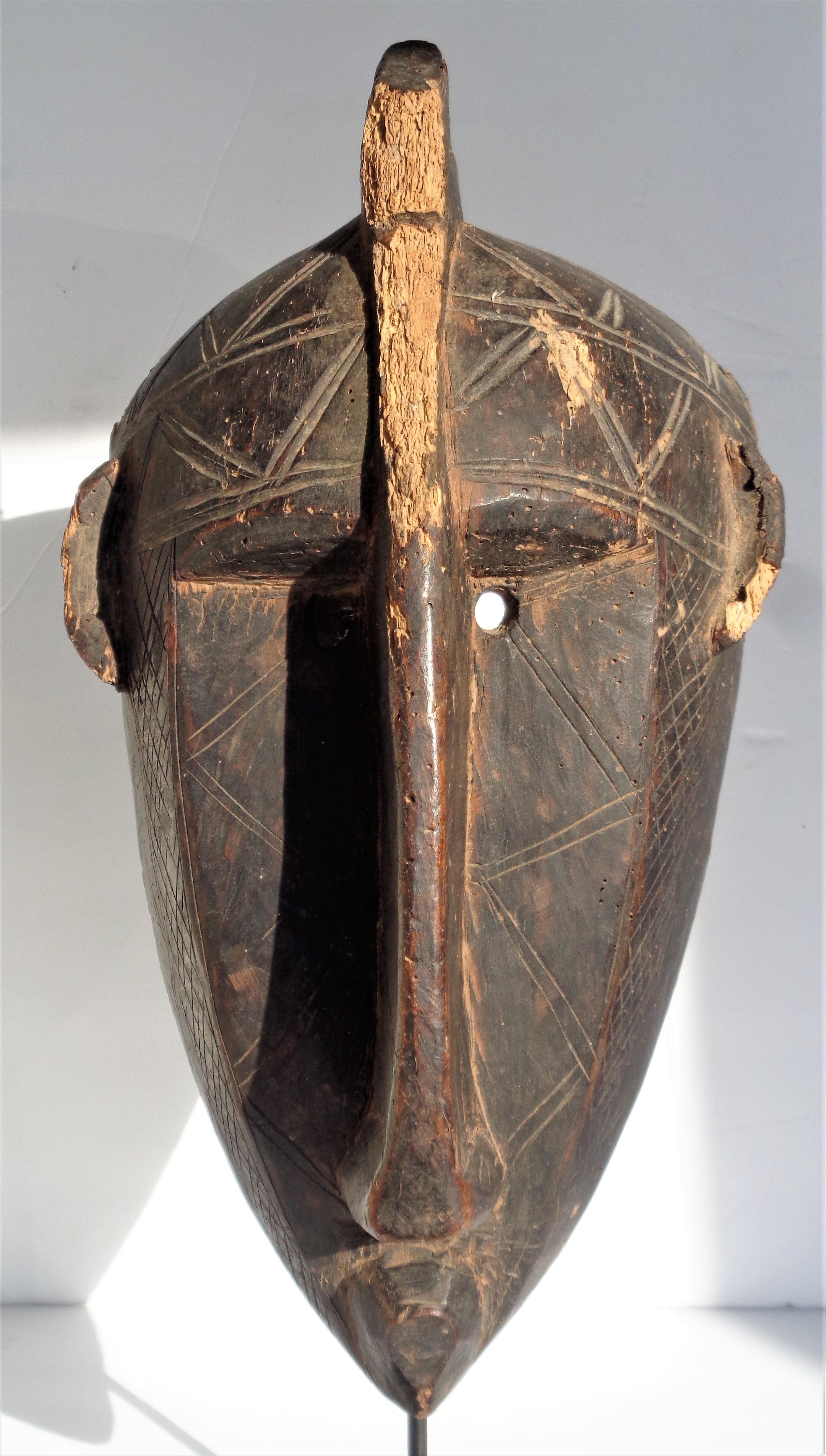 Bamana mask from Mali with deep set eyes, small highly placed ears, head crest extending down joining long prominent nose and the face with zig-zag patterns. Beautifully aged original old surface color with areas of  wood loss, genuine wear and some