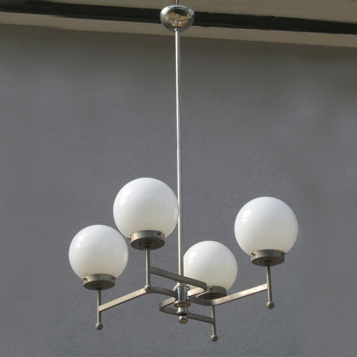 Exceptional and rare Bauhaus chandelier in nickel plated brass and original opaline spheres.
The chandelier is from early 1930s iand made in a form of Japanese Buddhist Manji symbol, a predominant Buddhist symbol in Japan.
The ‘counterclock’ Manji