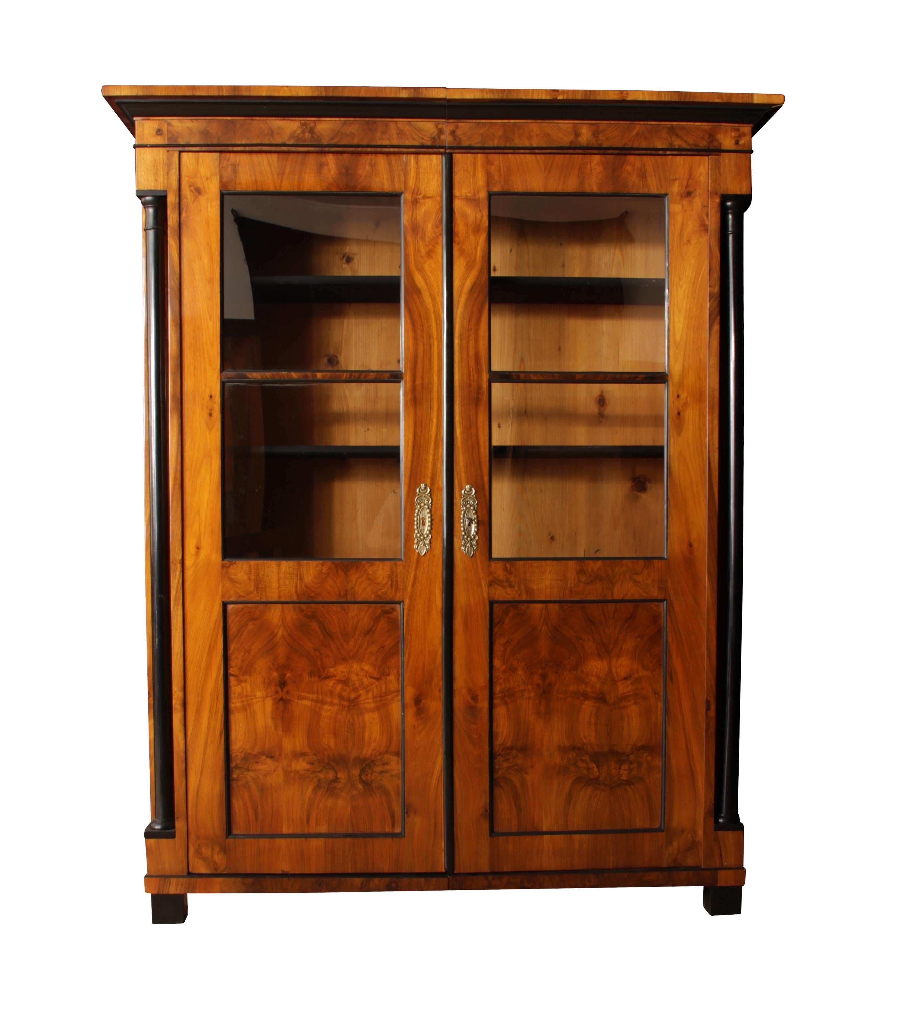 Wonderful early Biedermeier bookcase / library from South Germany around 1820.

The veneer at this unique furniture is of best quality and has a very beautiful grain at the front and both sides. 
The bookcase has two black columns that are very