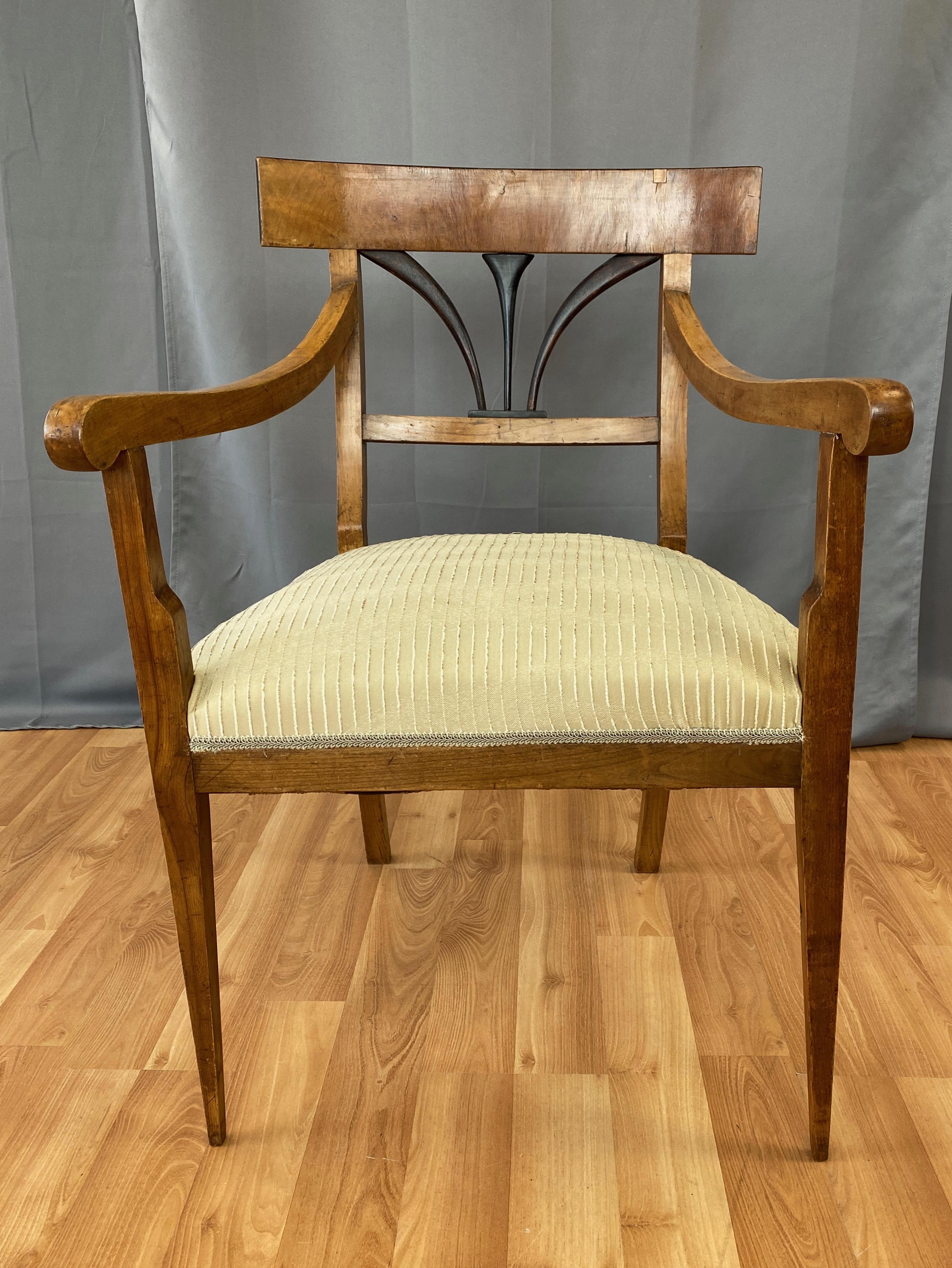 A very handsome circa 1825 Biedermeier armchair in fruitwood and ash with ebonized accents and upholstered seat.

Restrained neoclassical lines exhibit subdued sophistication. Understated yet elegant details throughout, including needle-like front
