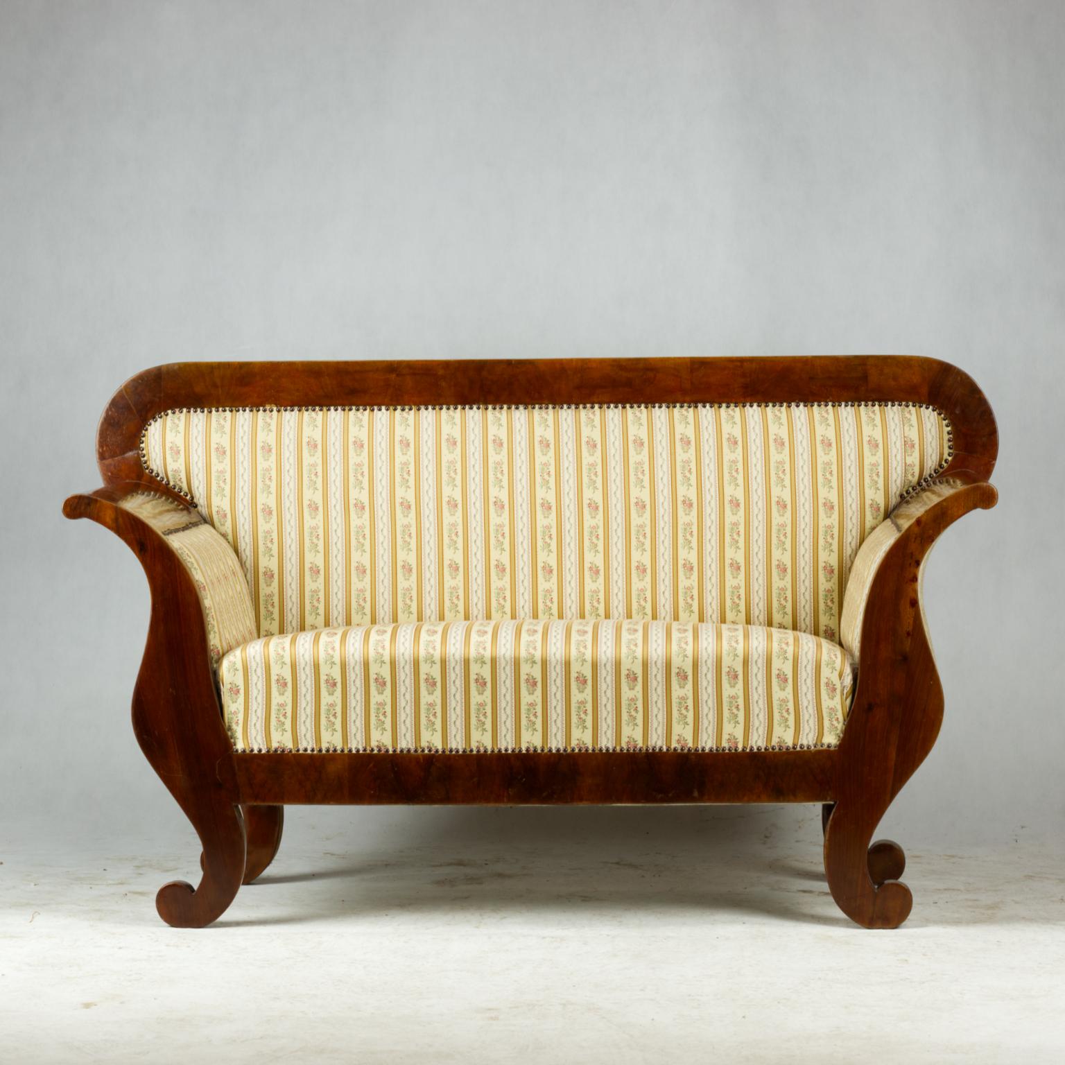 Das Sofa stammt aus dem frühen Biedermeier zu Beginn des 19. Jahrhunderts. Der Korpus des Sofas besteht aus Fichtenholz und wurde mit einem sehr schönen dicken Walnussfurnier überzogen. Das Sofa ist in gutem Zustand. Die Polsterung ist nicht das