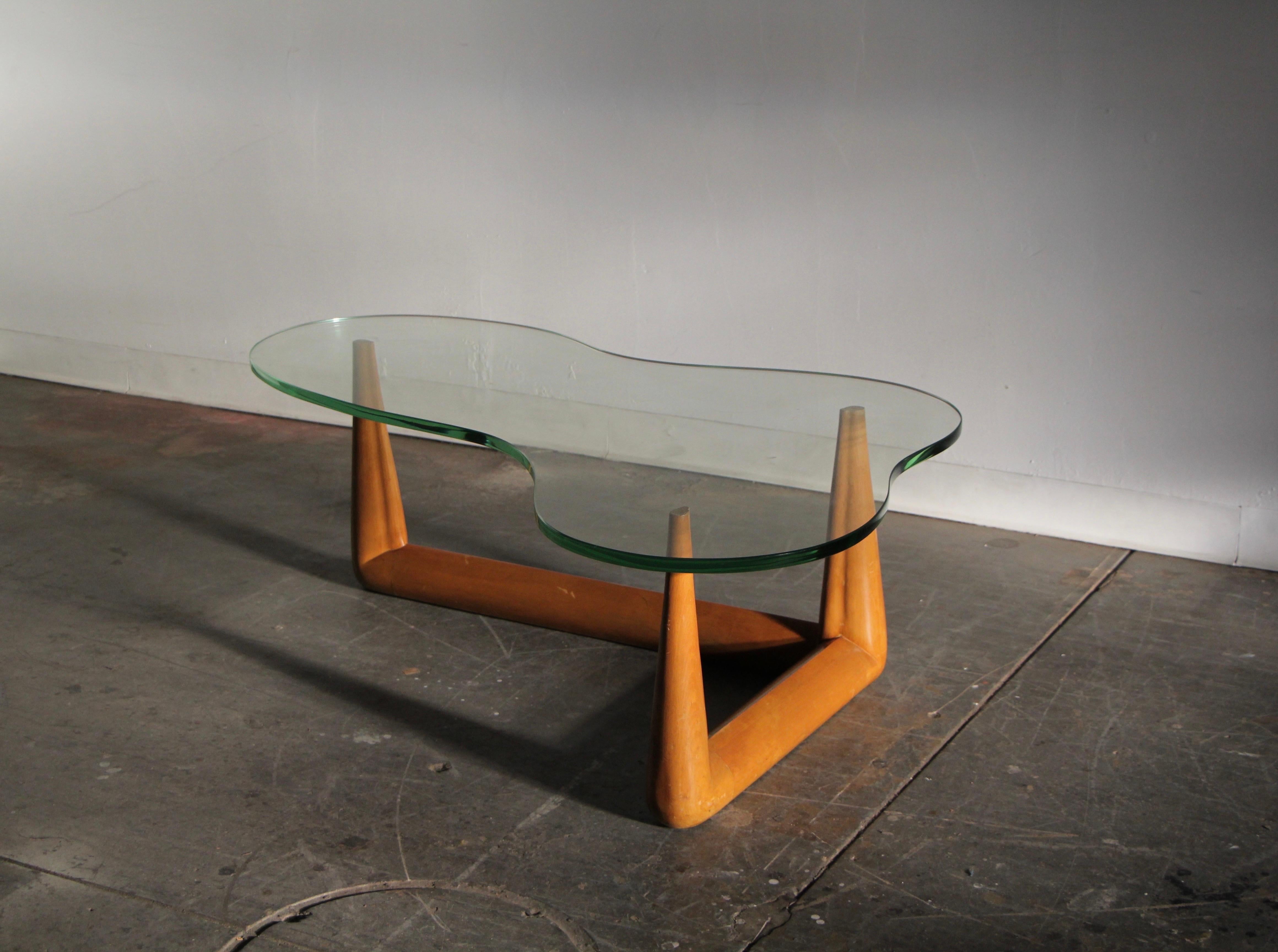 An exception, early, and completely original example of T.H. Robsjohn-Gibbings' biomorphic coffee table for Widdicomb, circa 1950s. Consisting of a sculpted, solid maple, three-prong base, and a sinuous, organic form, Uranium glass top, this design