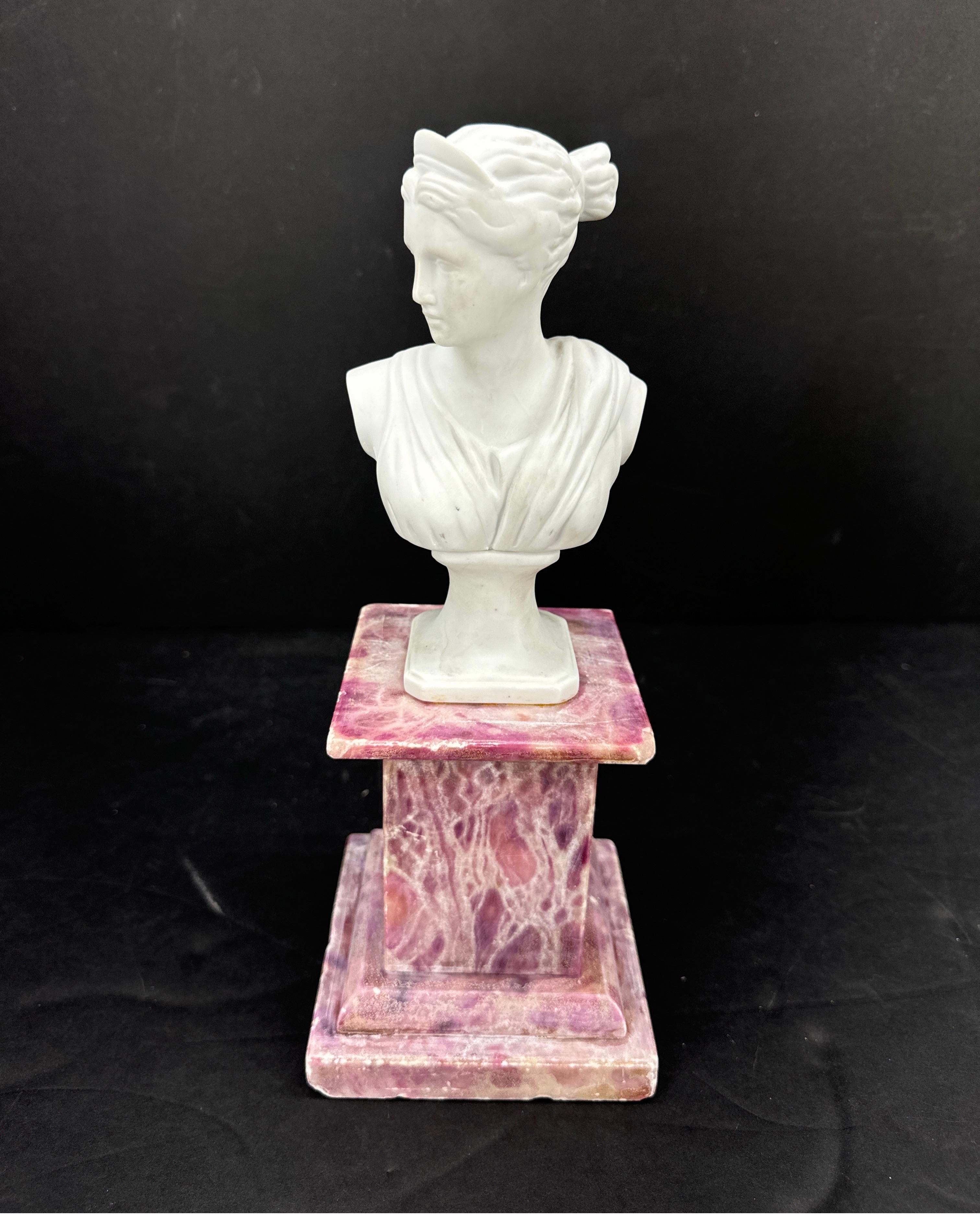 Piccolo busto di signora in porcellana biscuit posto su un piedistallo quadrato vintage in marmo rosso. Questa scultura a forma di mensola sarebbe perfetta come pezzo decorativo su un tavolo in un salotto o per una biblioteca su uno scaffale. 