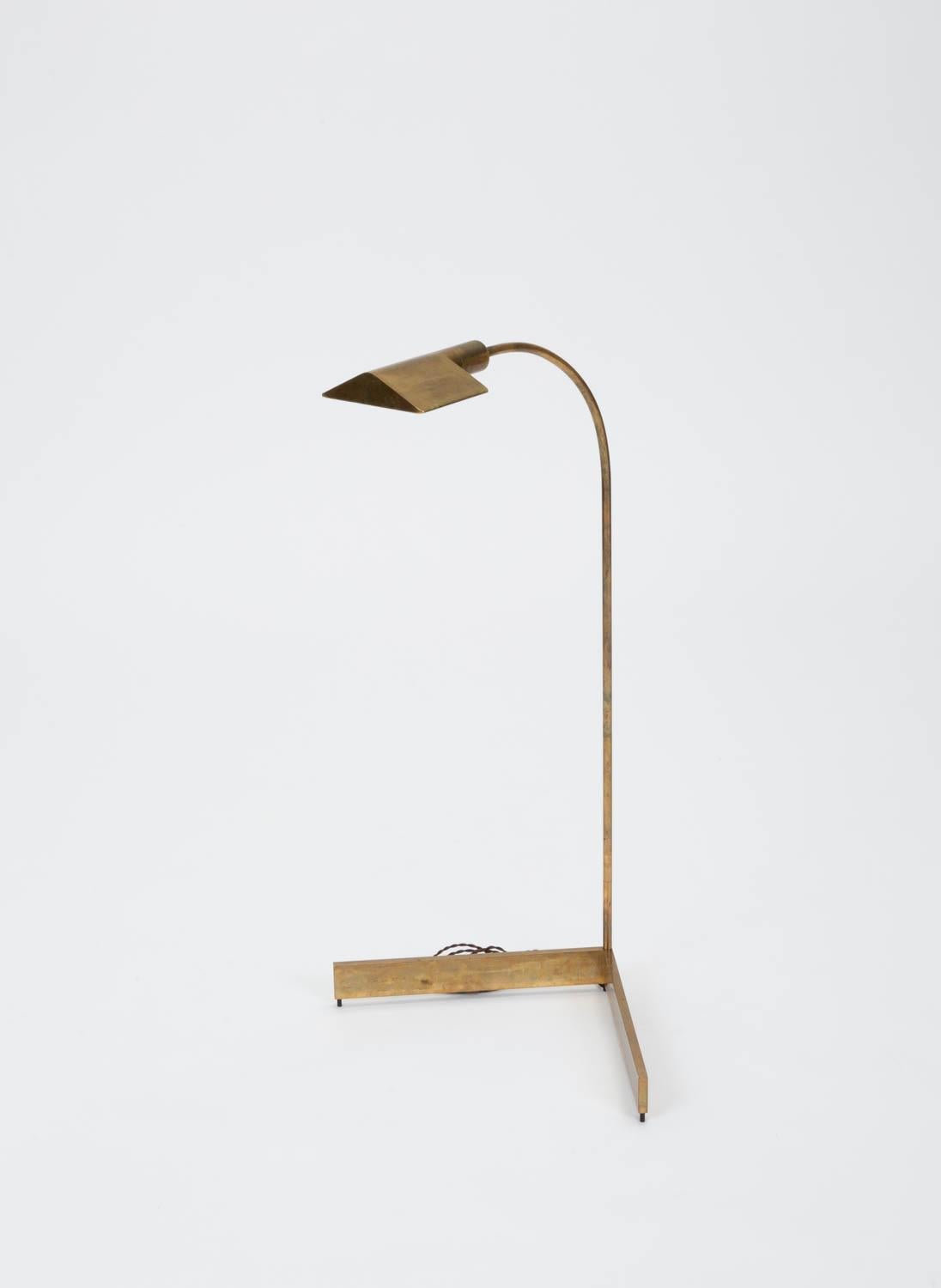 Designed in the 1970s, the brass floor lamps by Cedric Hartman are an enduring design Classic. The modernist floor lamp features a triangular brass shade attached to a curved stem that offers focused task lighting. The arched brass pole terminates