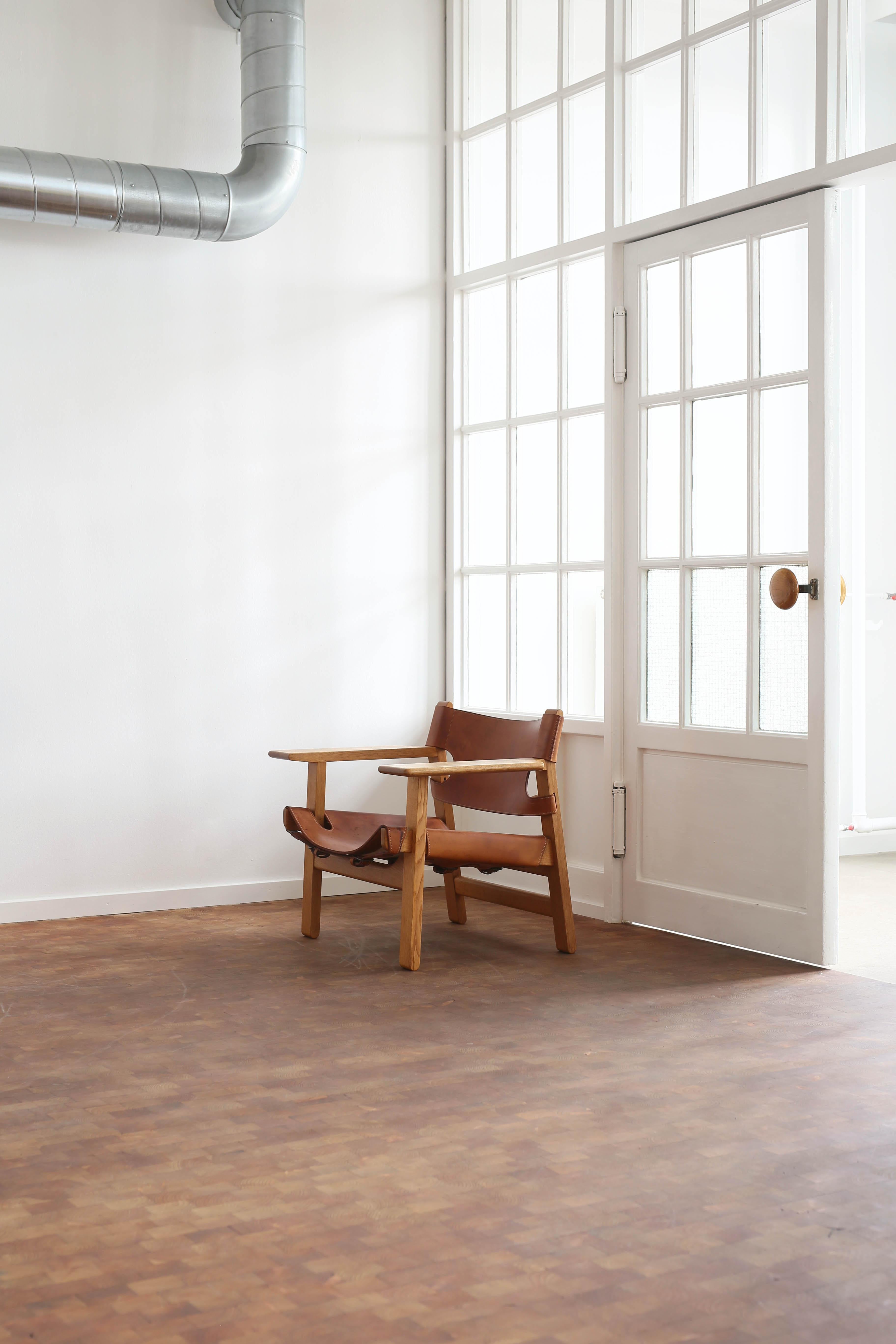 An early version of Børge Mogensen's iconic 'The Spanish chair' with frame of solid oak, mounted with grain leather. 

Designed by Borge Mogensen 1958 and executed by Fredericia Furniture with leather work by Dahlman Saddlers, Copenhagen.

Good
