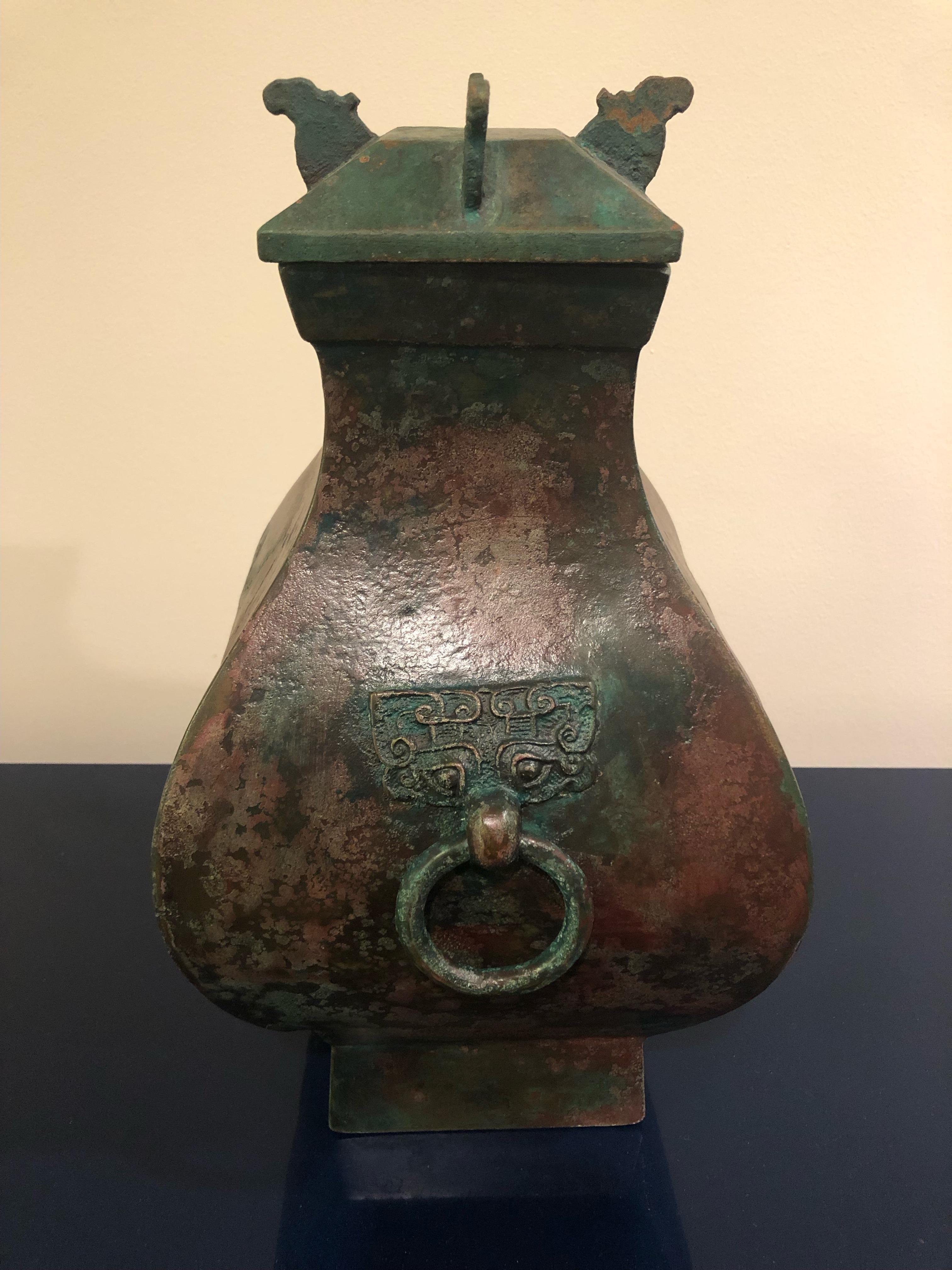 Very early, 206 BC to 220 AD, square shaped bronze fang hu bronze vessel would have functioned as a ritual container for the storage and transportation of sumptuous wines. This refined fang hu is essentially unadorned, save for two decorative Tao