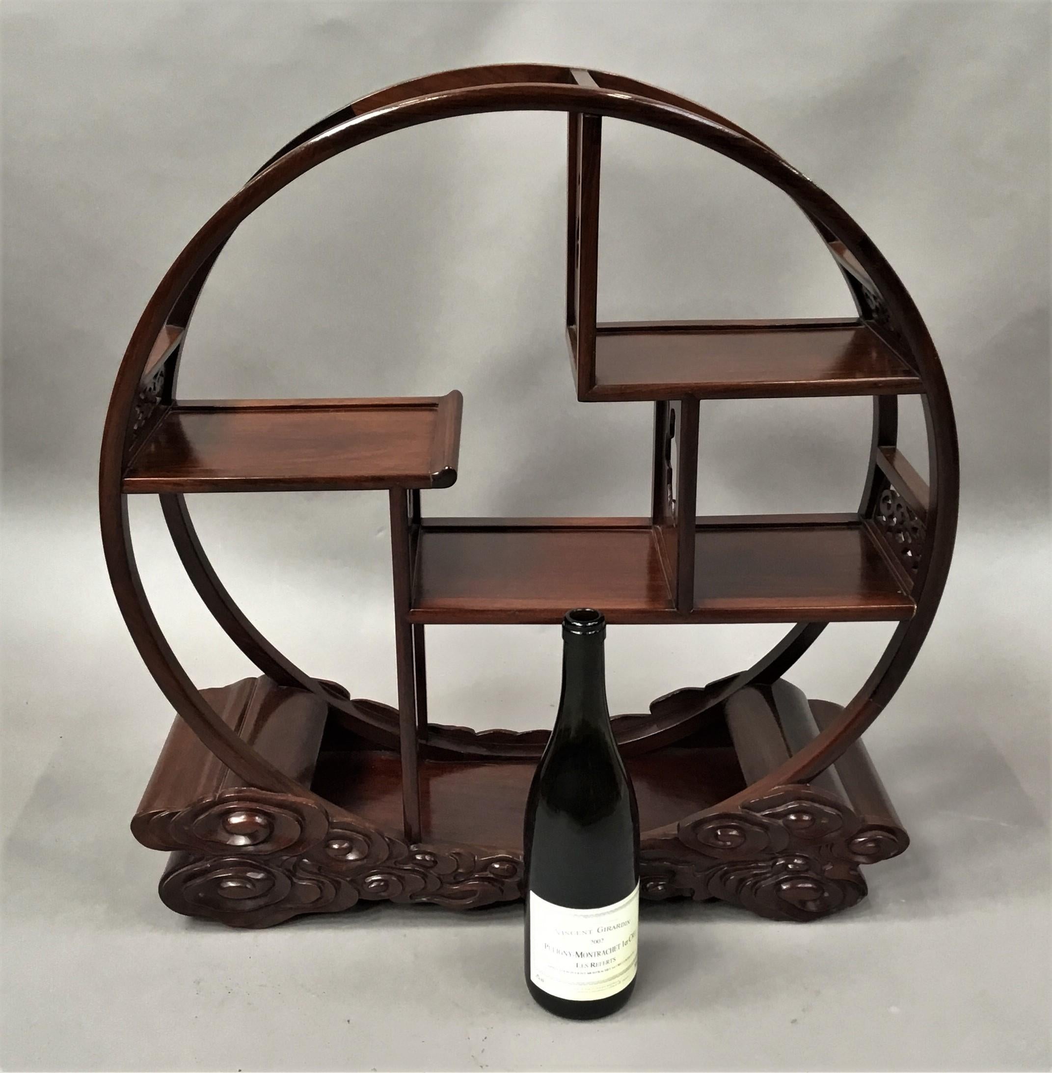Early 20th century Chinese Hongmu display stand being freestanding and of unusual circular design. The circular frame with foliate pierced panels to the sides, the well figured panelled shelves of an asymetrical design with pierced leaf partition